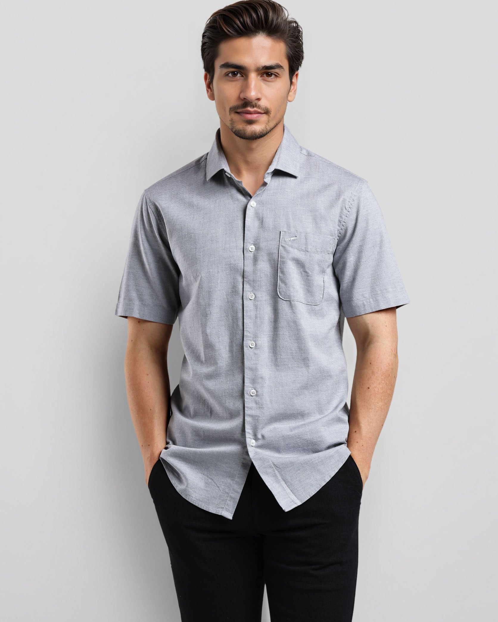 Man wearing a light blue checkered shirt and black pants against a gray background