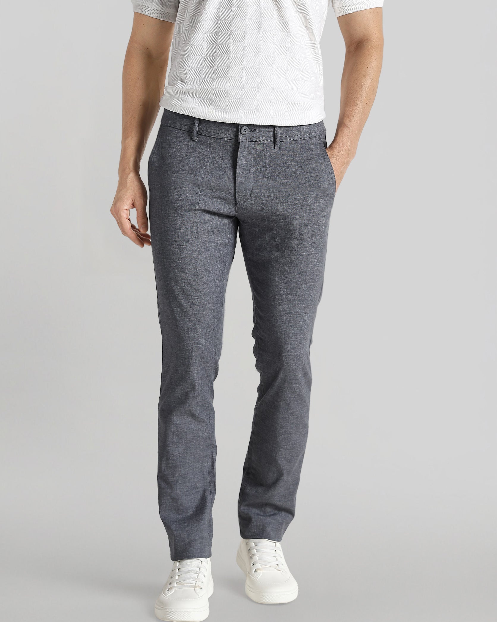 Person wearing gray pants and a white shirt on a plain background