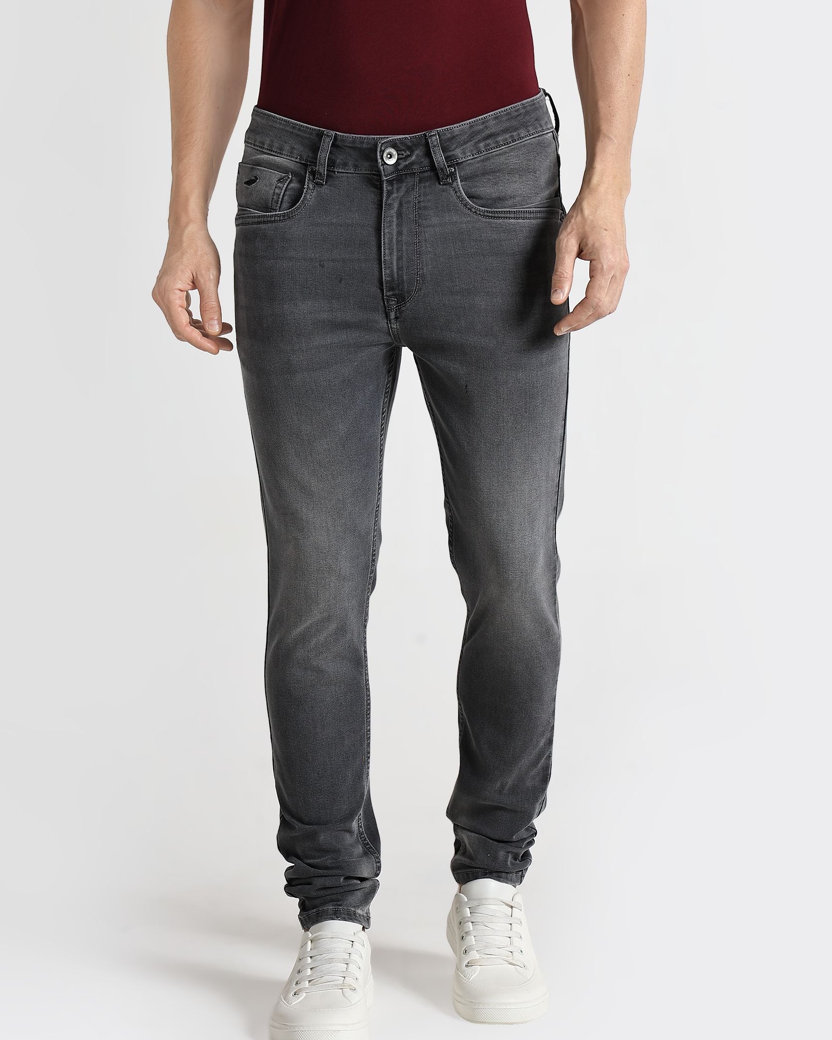 Person wearing gray jeans and a maroon shirt on a white background