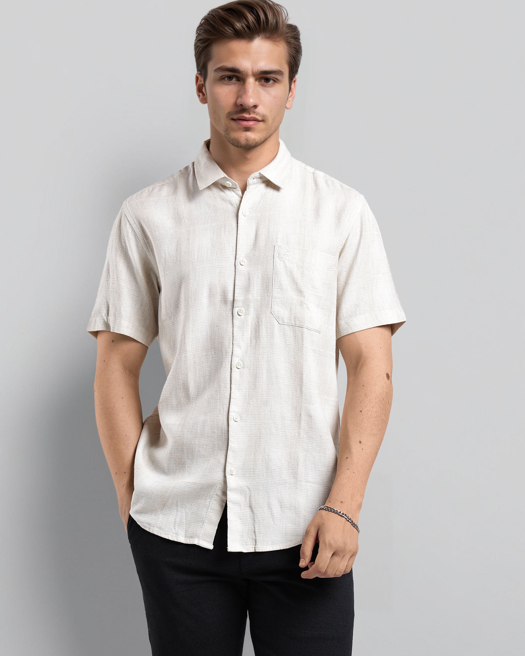 Man wearing a white short-sleeve shirt against a gray background