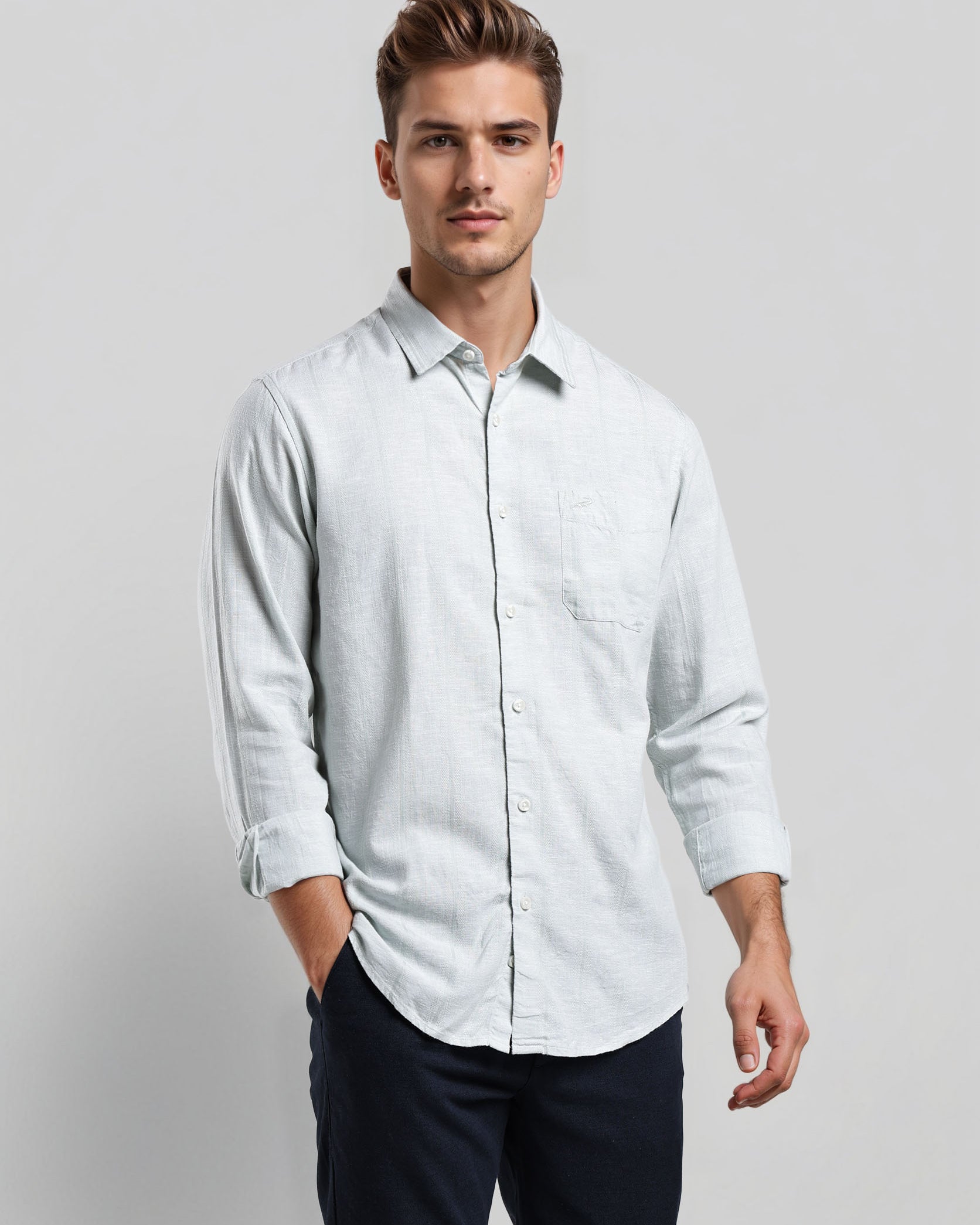 Man wearing a light blue shirt and dark pants on a plain background