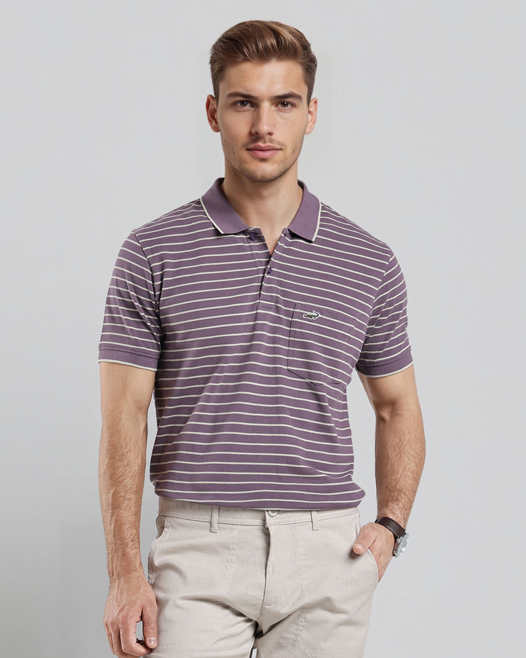 Man wearing a striped polo shirt and beige pants against a plain background