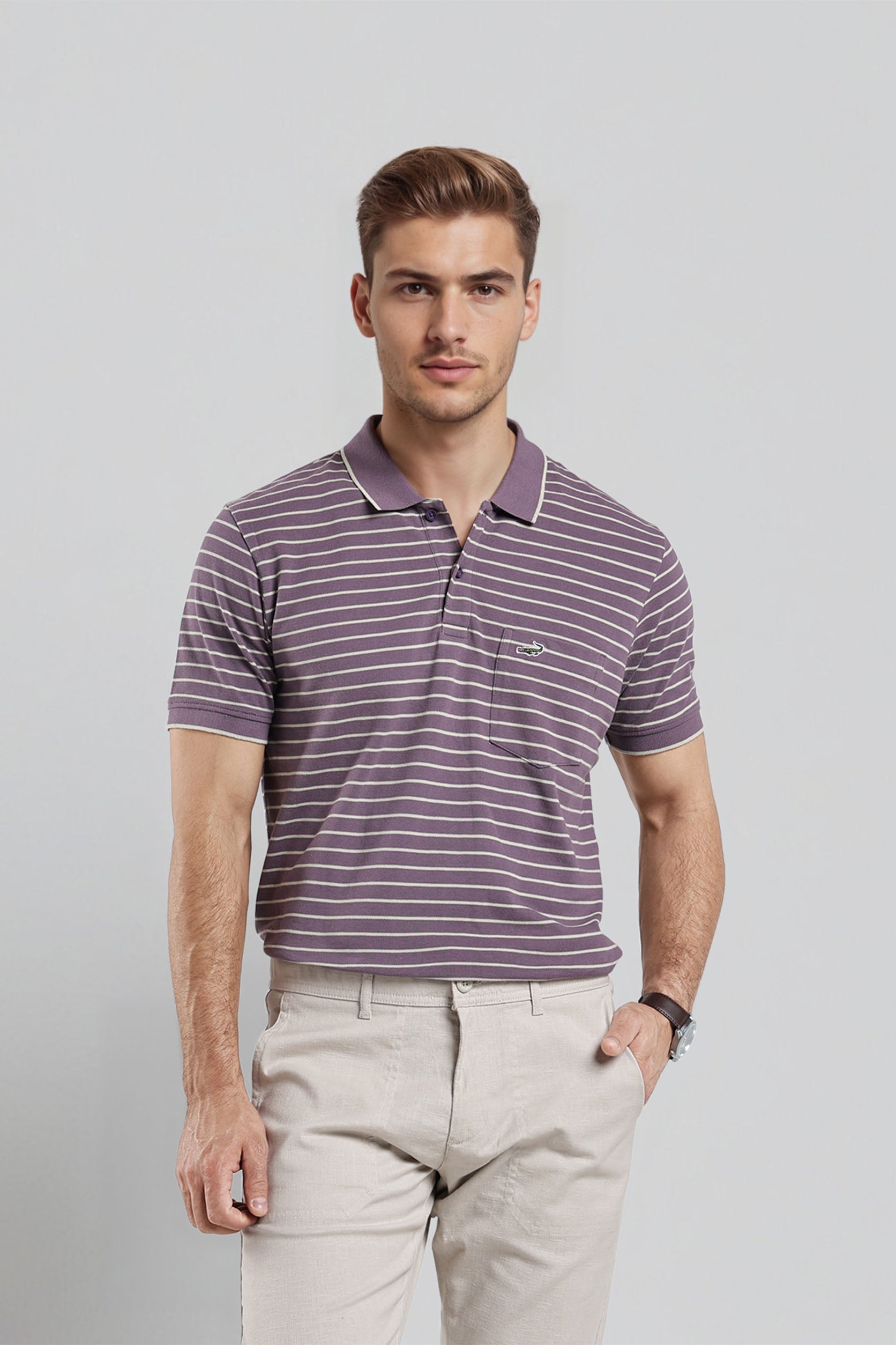 Man wearing a striped polo shirt and beige pants against a plain background
