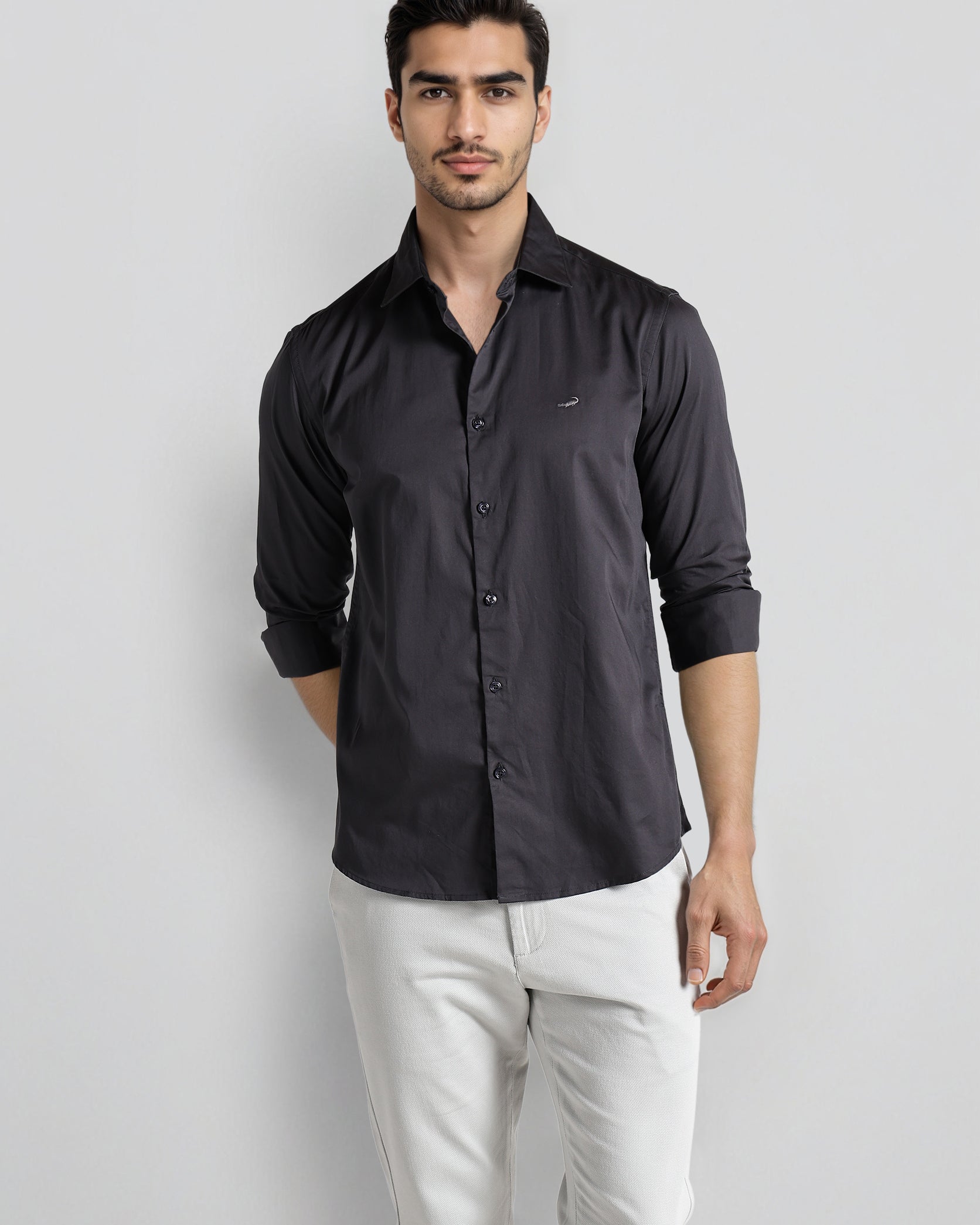 Man wearing a black shirt and white pants on a light gray background