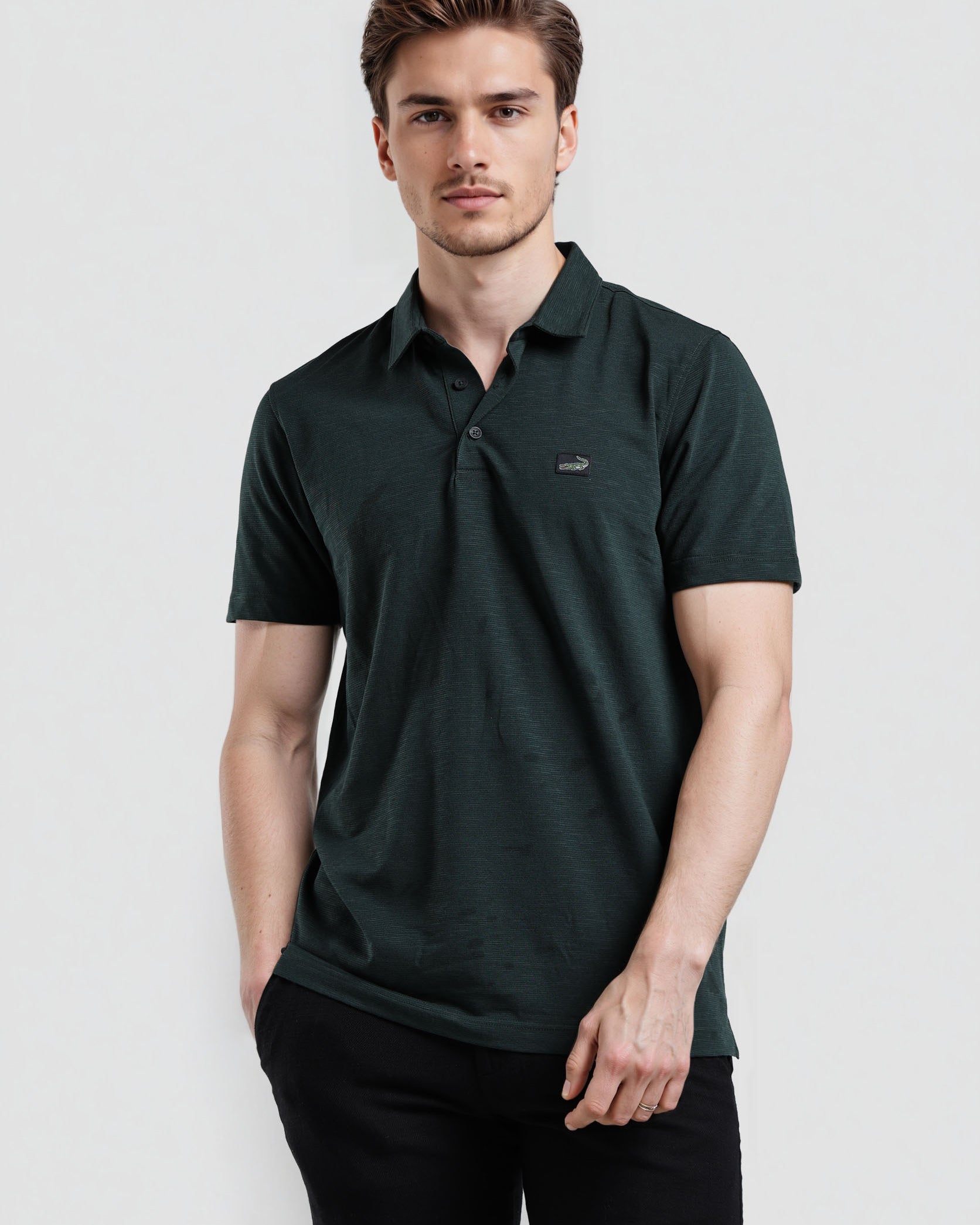 Man wearing a dark green polo shirt on a light gray background