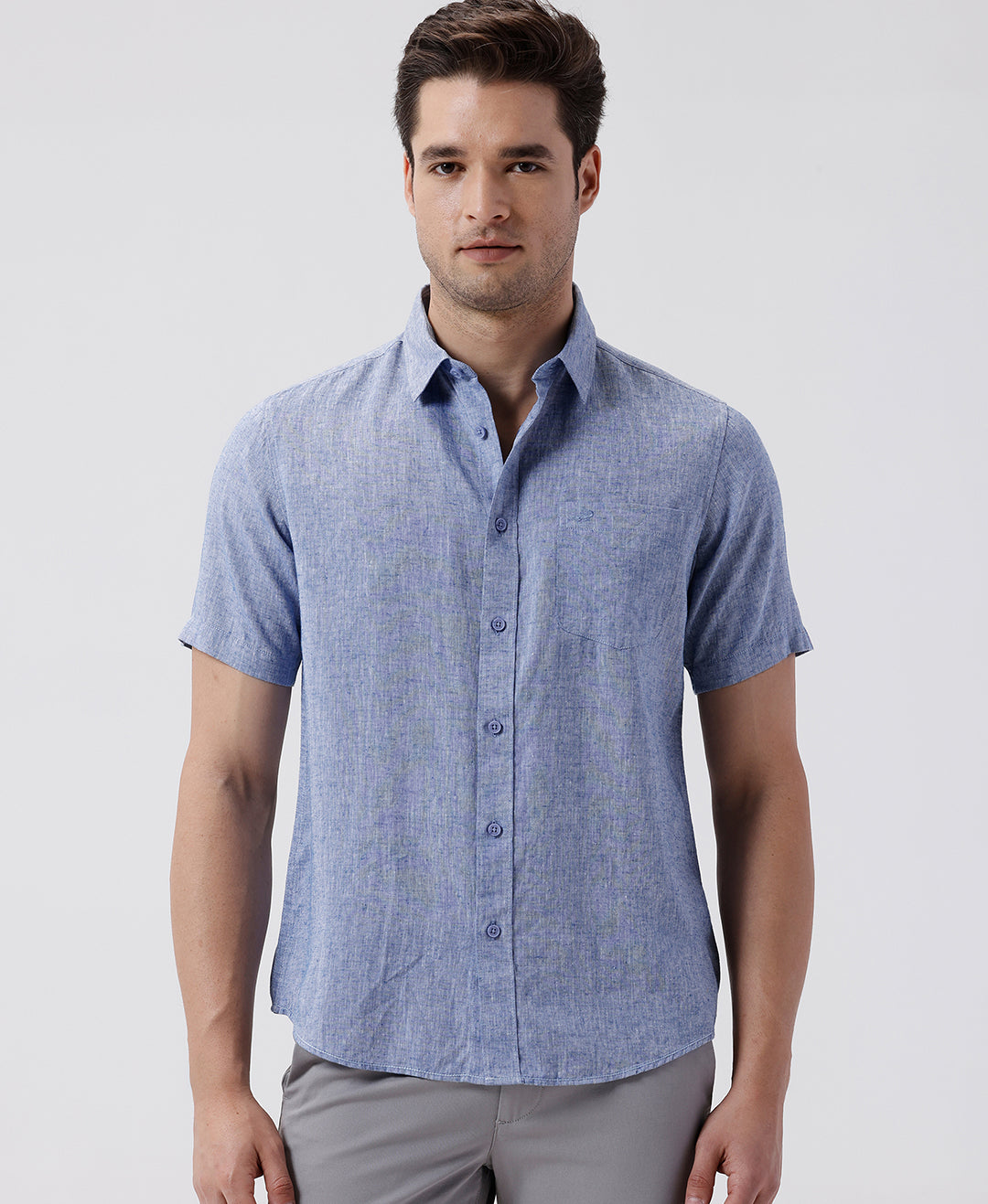 Man wearing a blue premium tensil linen shirt blue on a light gray background