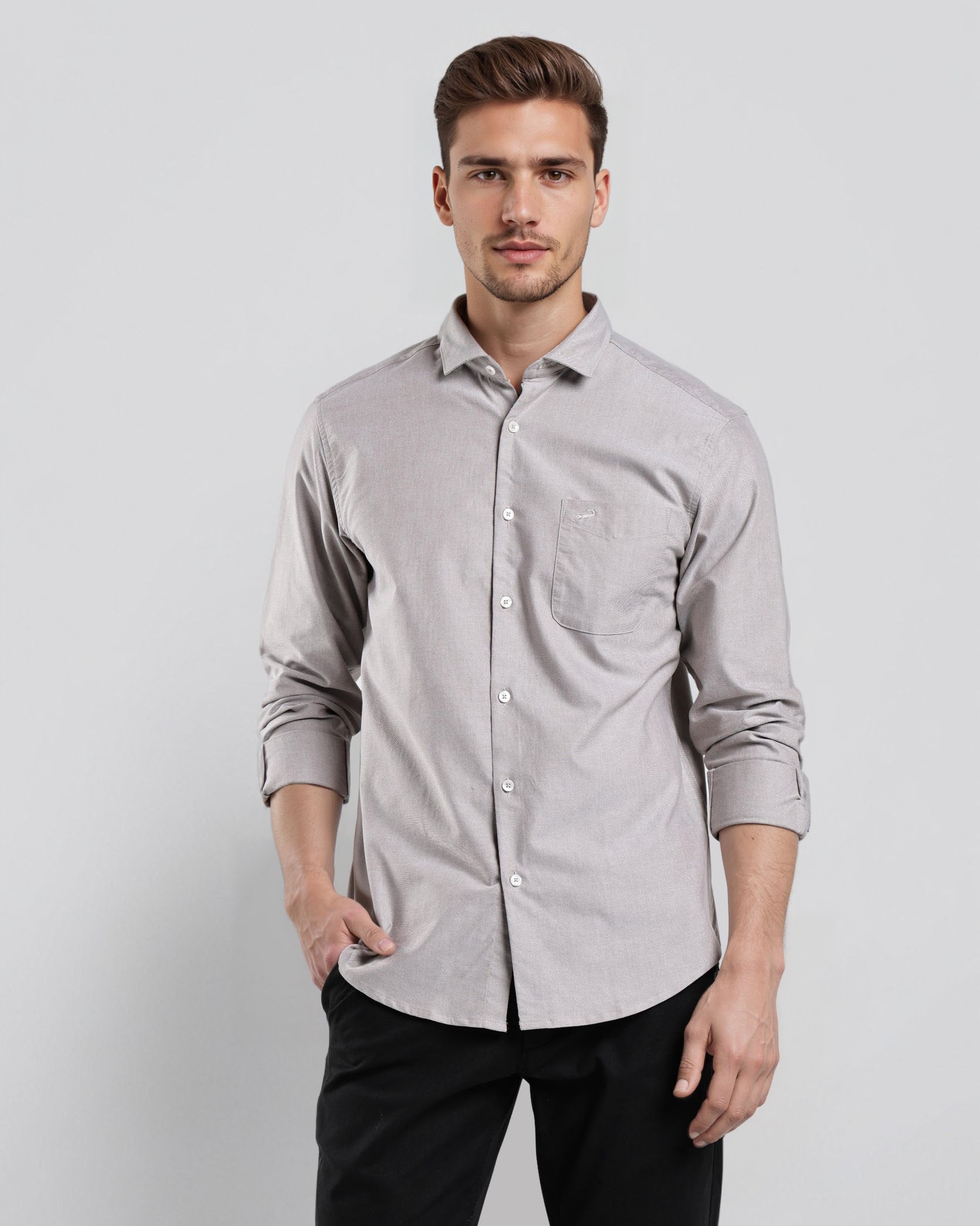 Man wearing a light gray button-up shirt and black pants against a white background