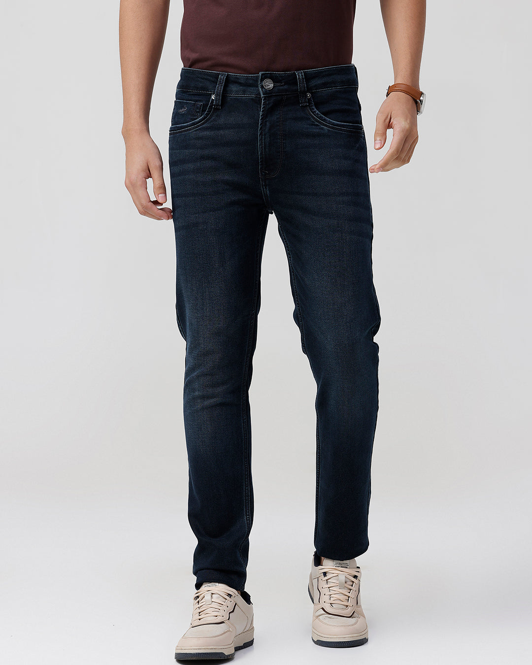 Man wearing a dark indigo knit slim fit jeans on a light gray background