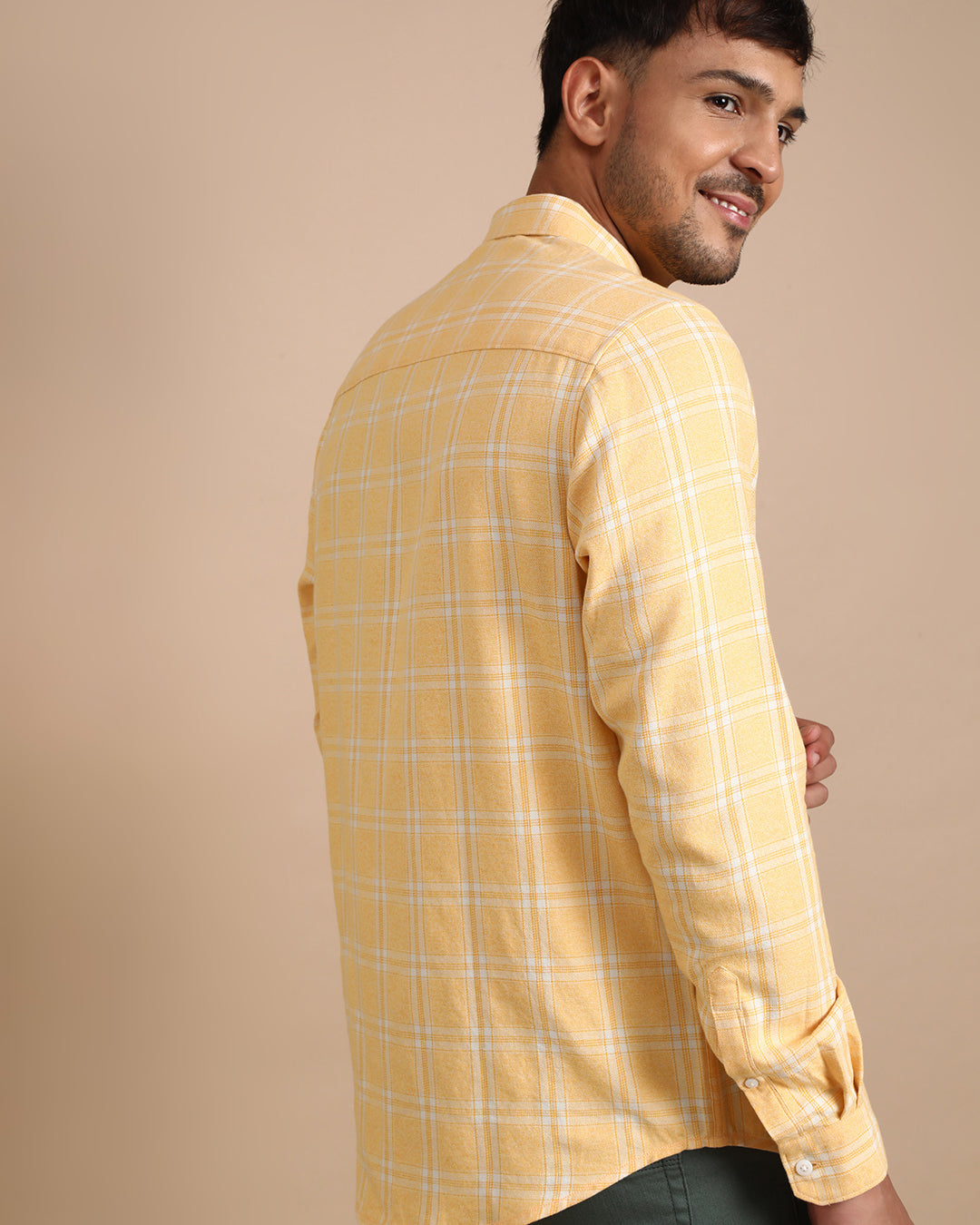 Man wearing a yellow casual yellow checked full sleeve 100% cotton shirt with casual styling on a gray background