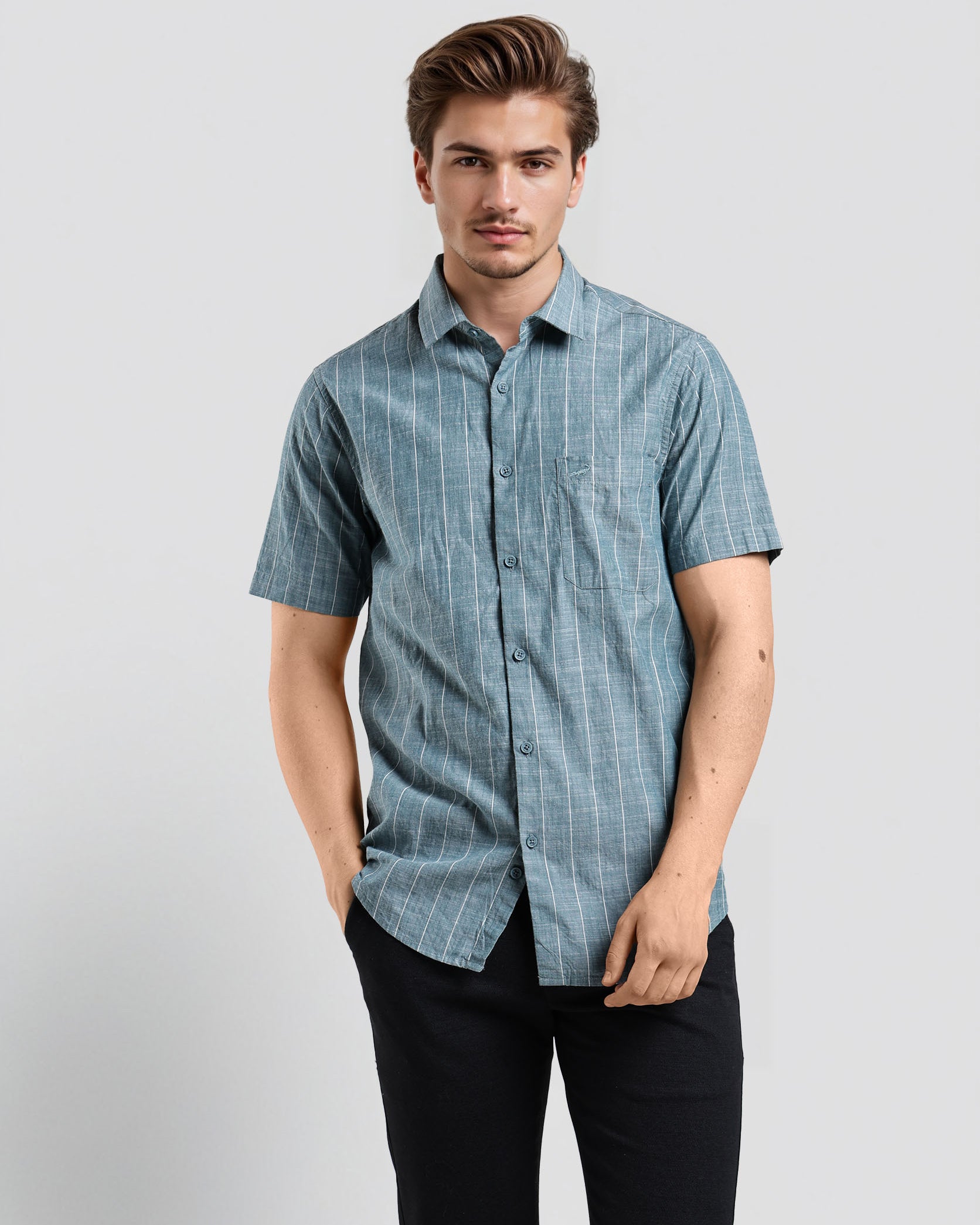 Man wearing a blue checkered shirt and black pants on a light gray background