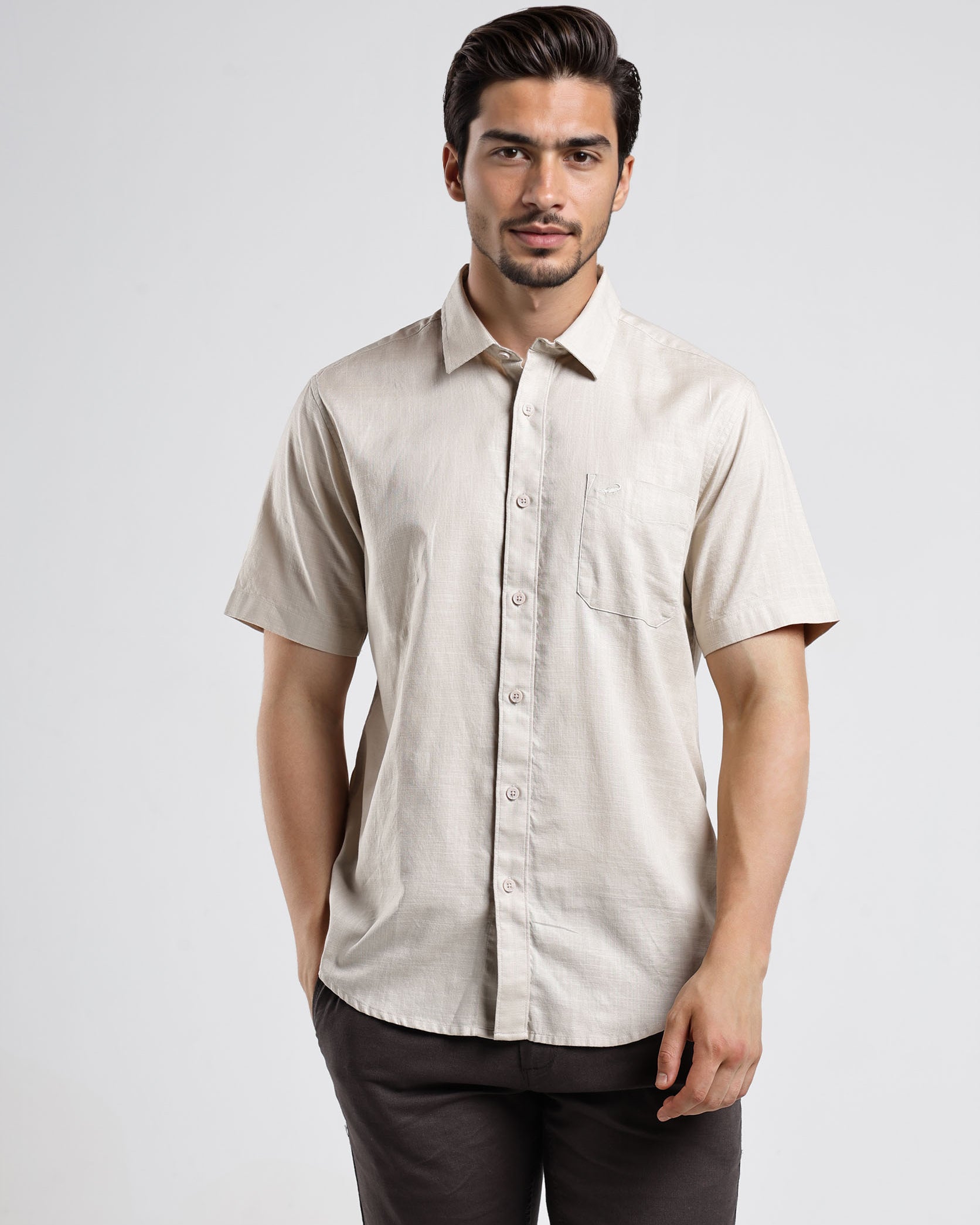 Man wearing a beige short-sleeve shirt against a white background