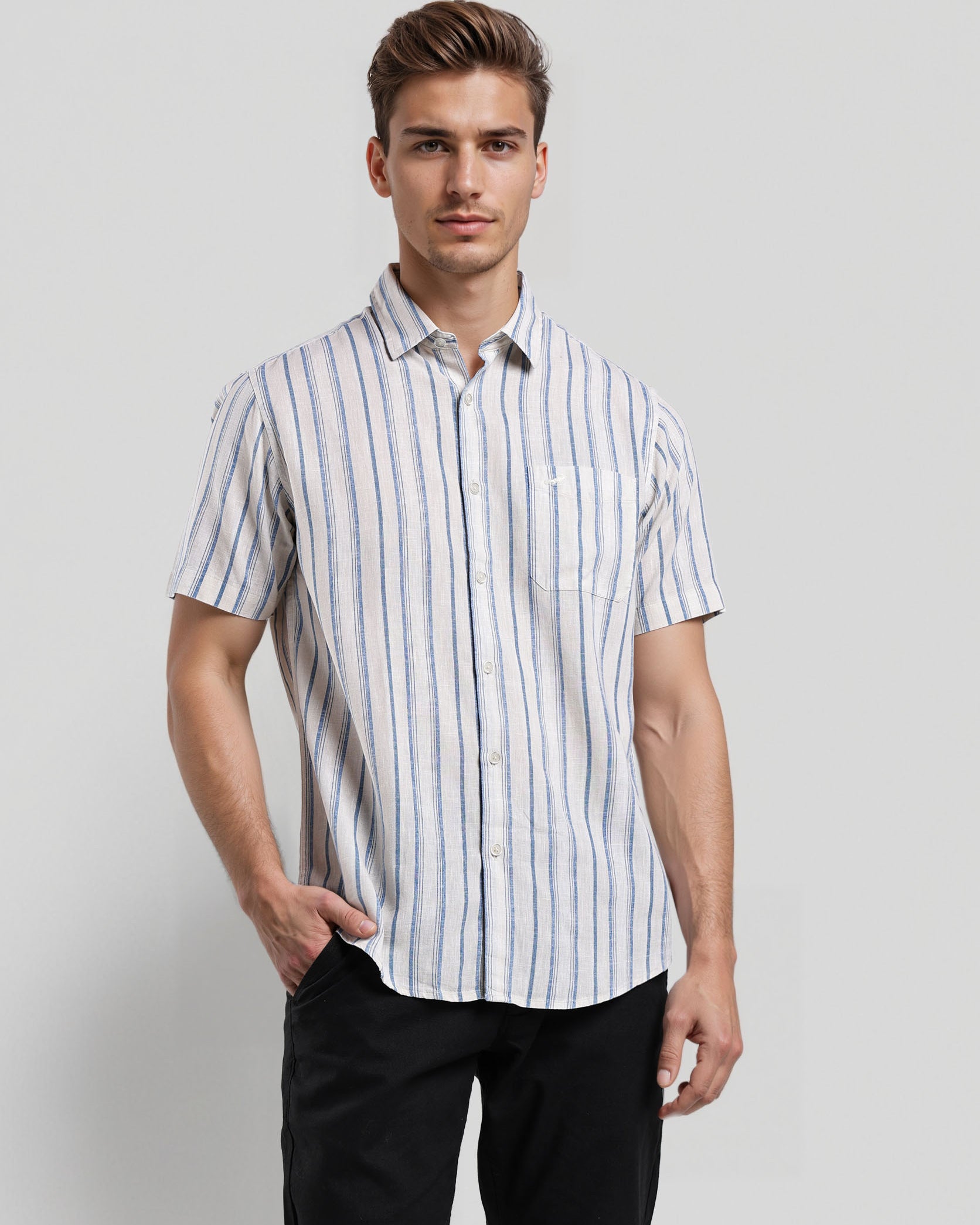 Man wearing a striped shirt and black pants against a plain background