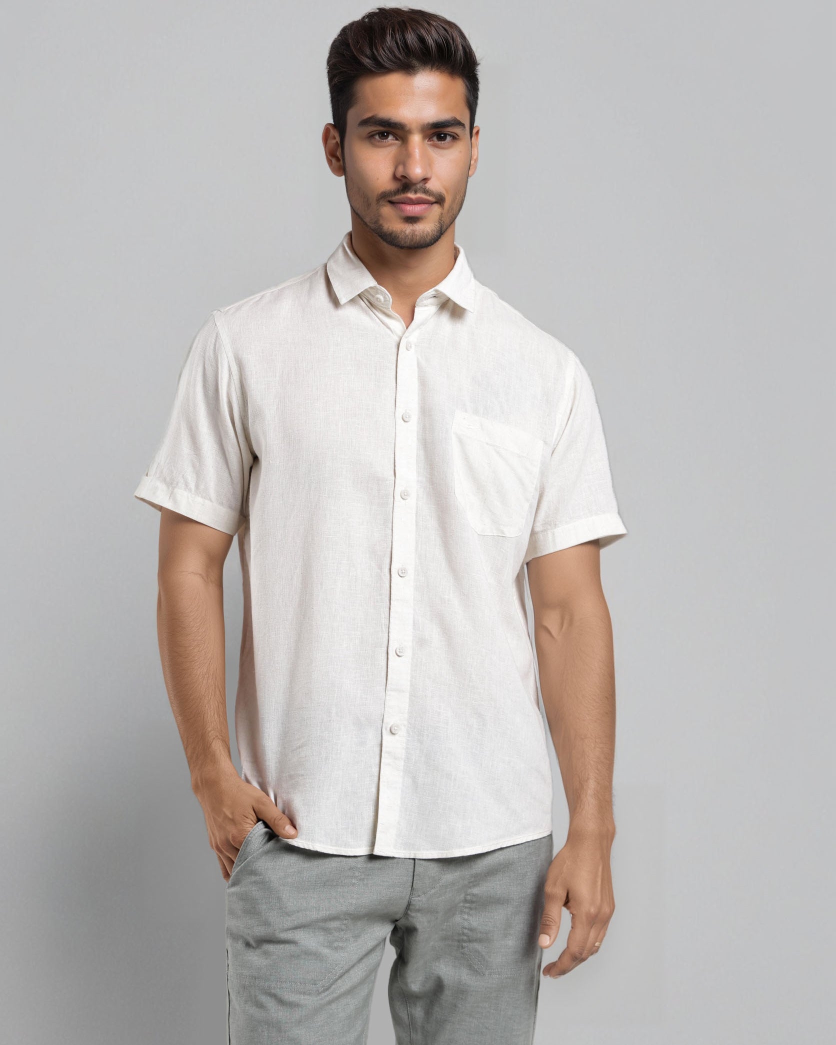 Man wearing a white short-sleeve shirt and gray pants against a gray background