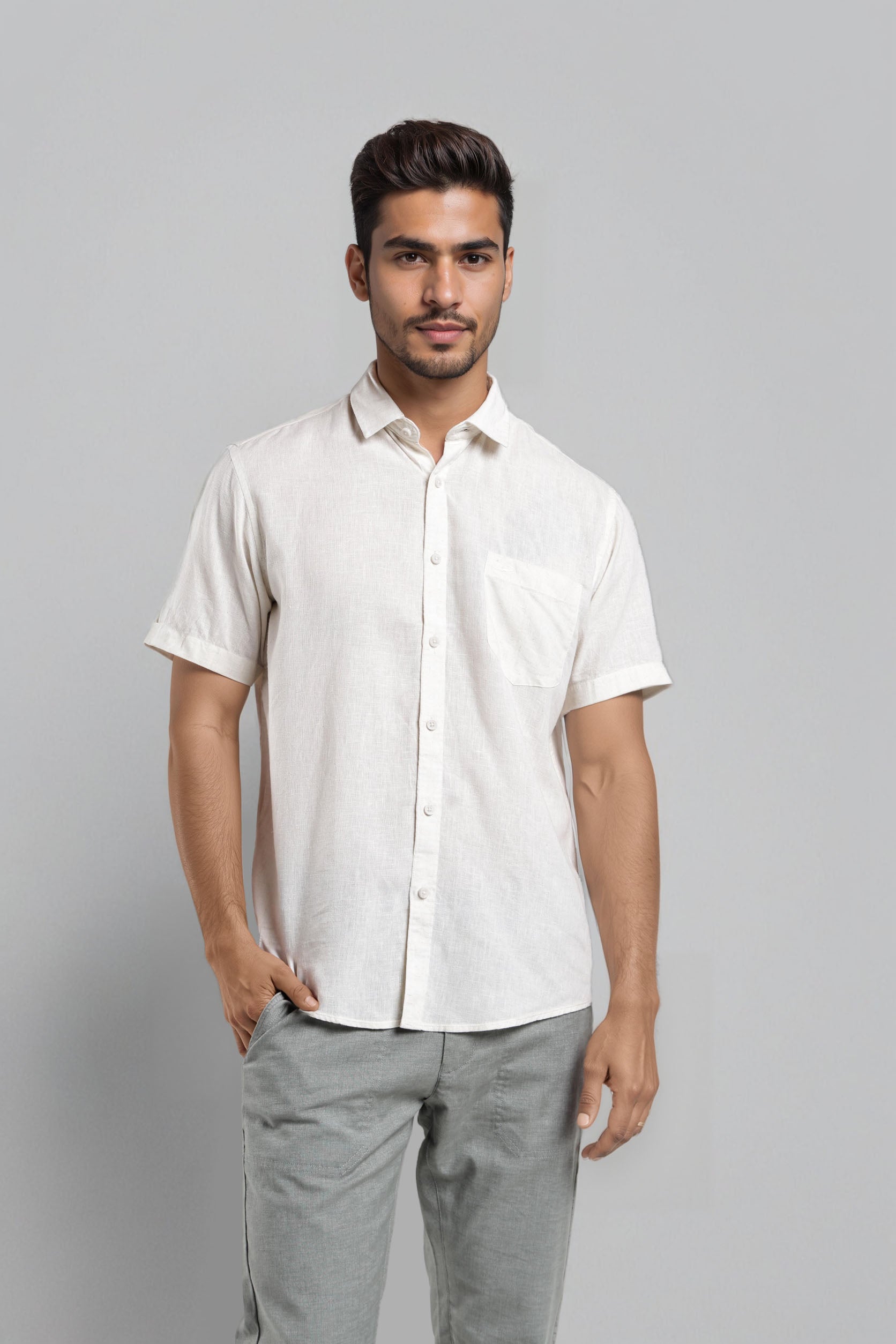 Man wearing a white short-sleeve shirt and gray pants against a gray background