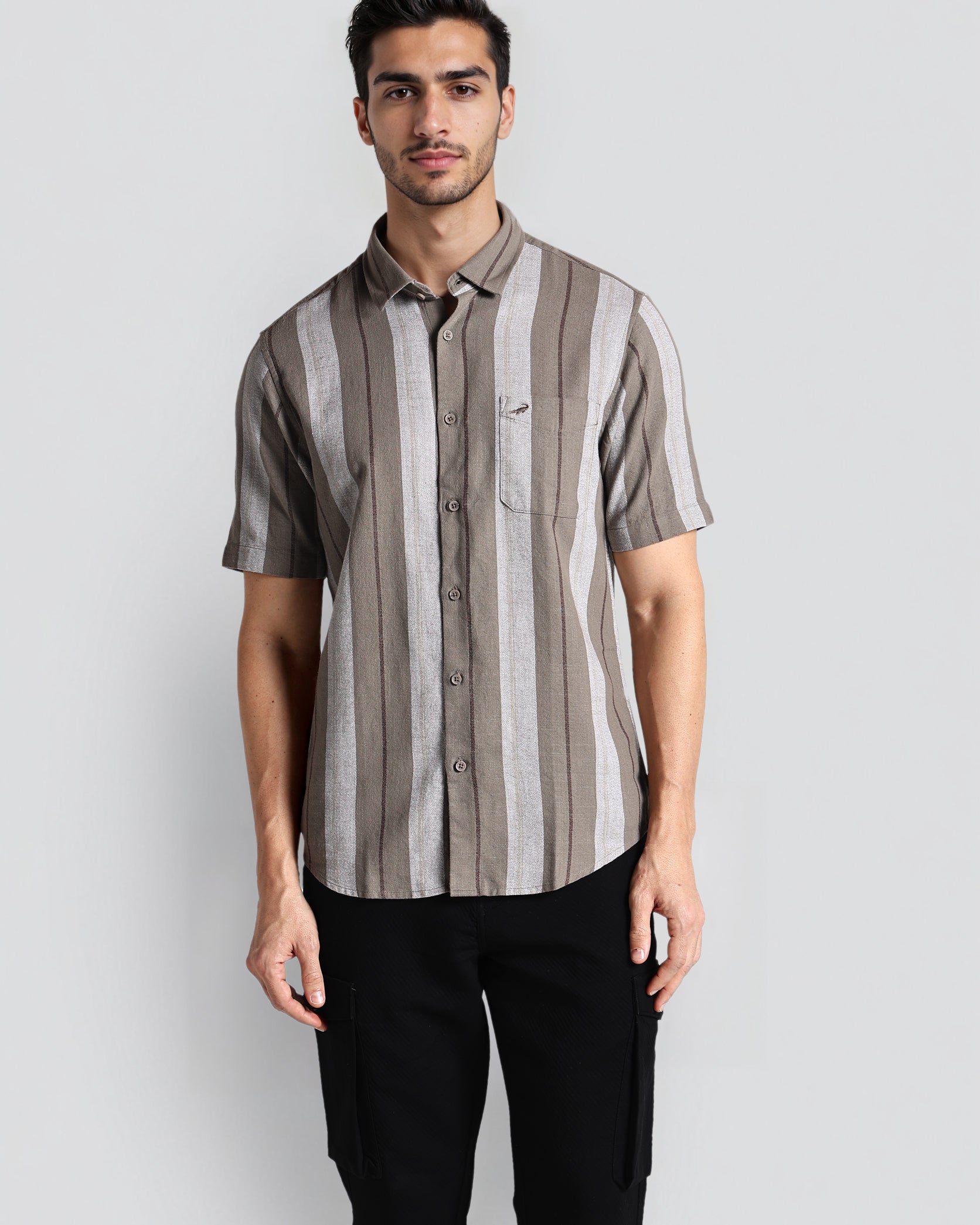 Man wearing a striped shirt and black pants against a plain background