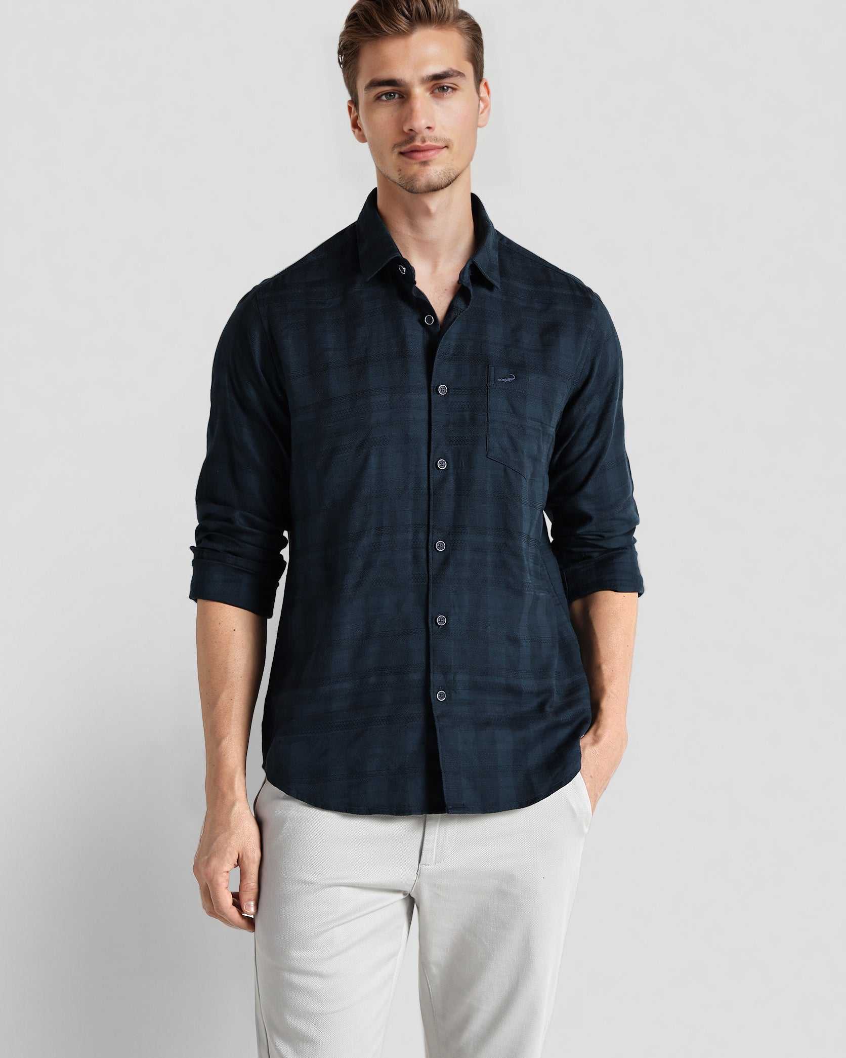 Man wearing a dark blue button-up shirt and light gray pants on a white background