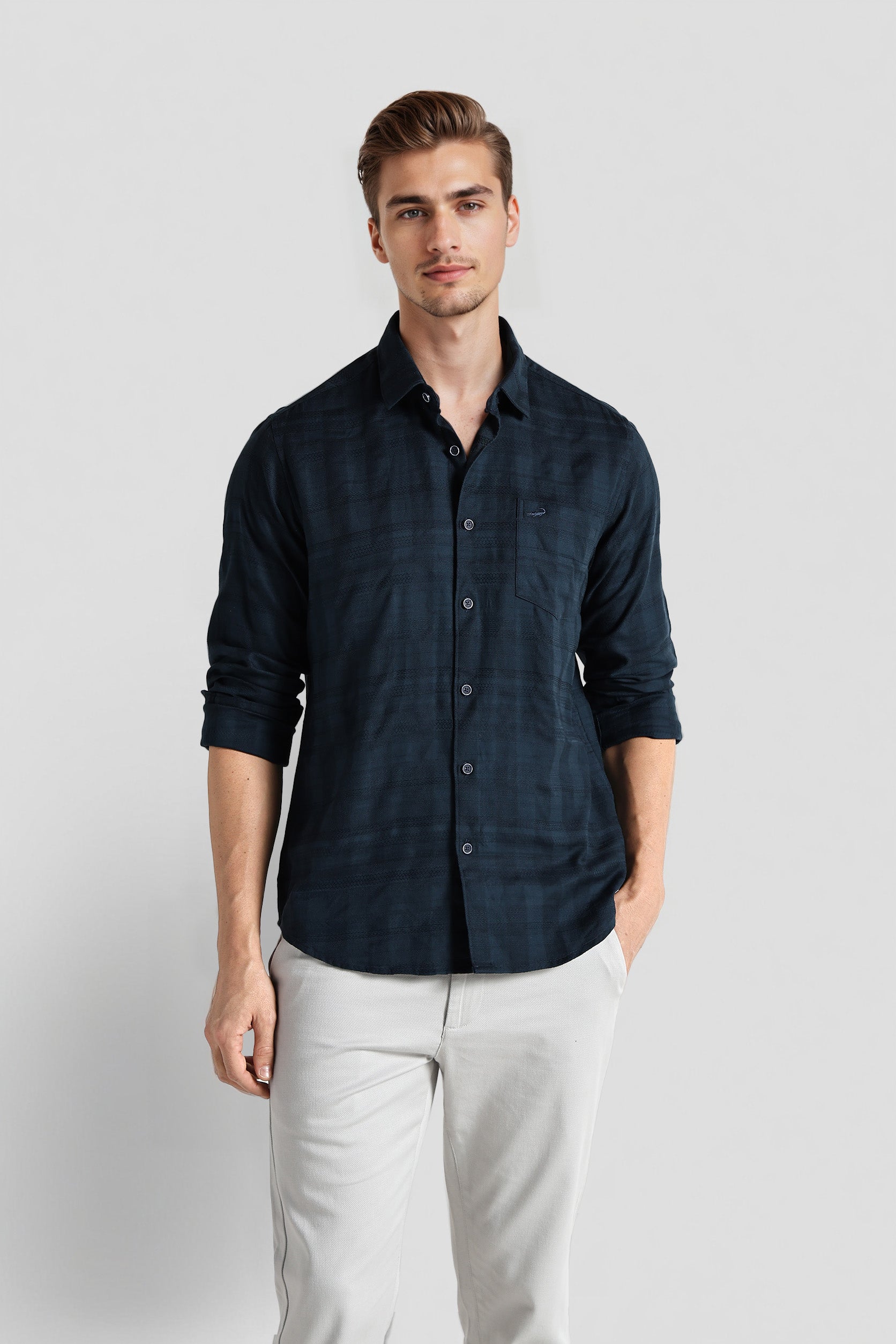 Man wearing a dark blue button-up shirt and light gray pants on a white background