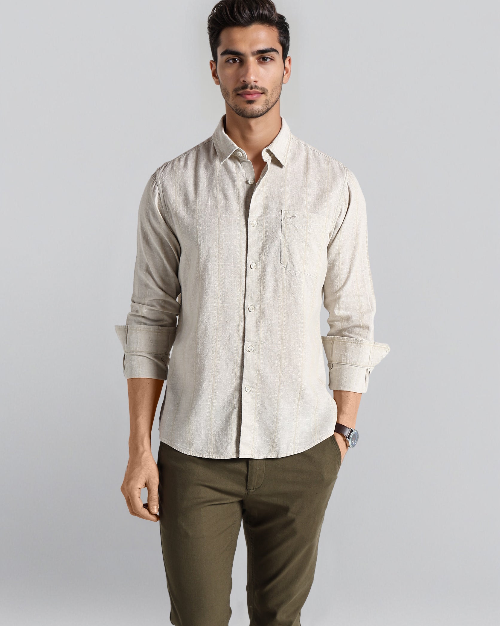 Man wearing a beige shirt and green pants against a plain background