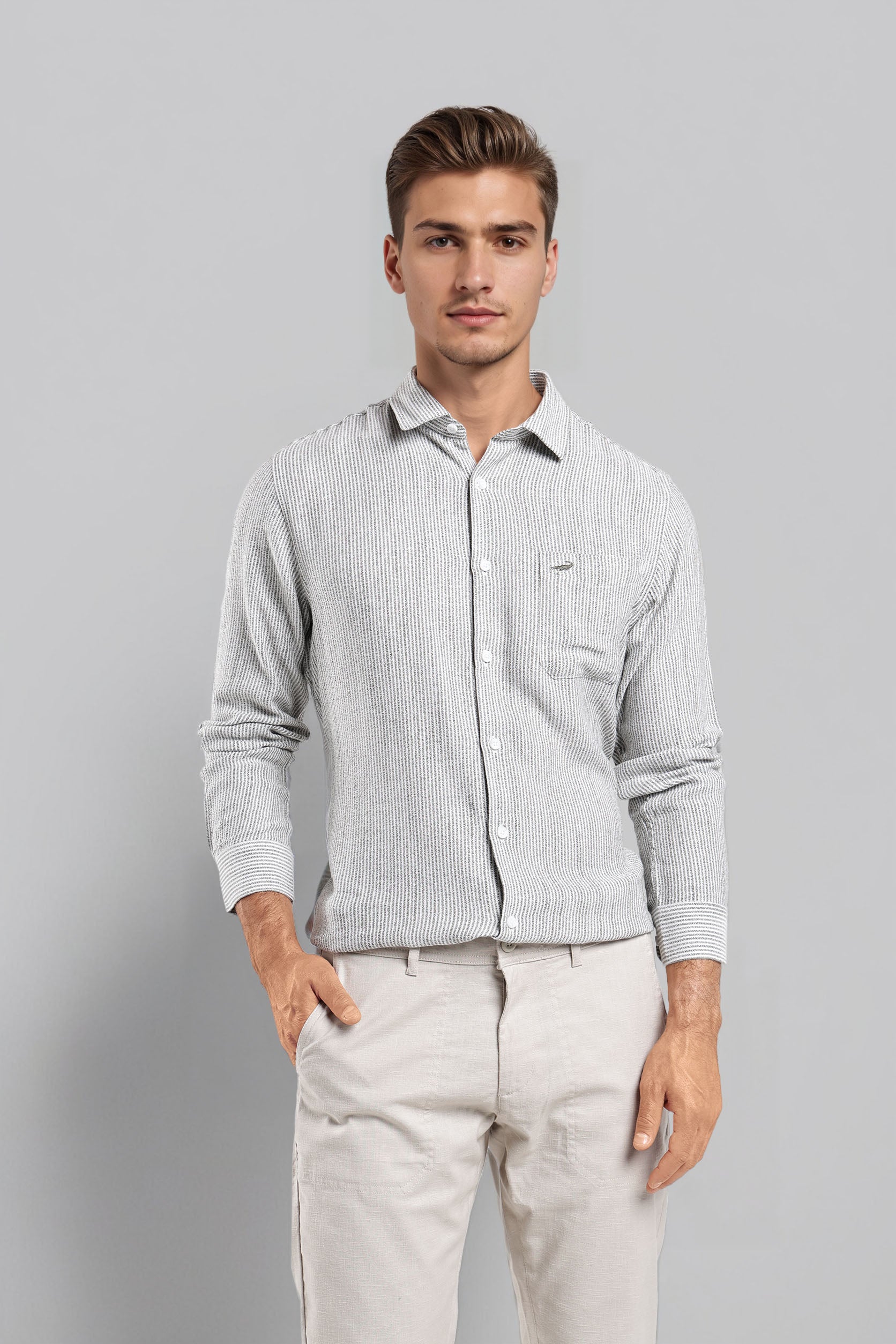 Man wearing a light gray striped shirt and beige pants on a gray background