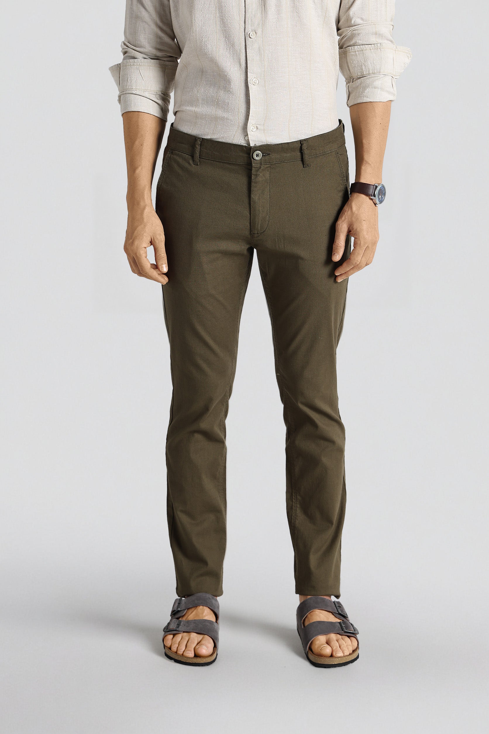 Person wearing olive green pants and a light-colored shirt on a white background