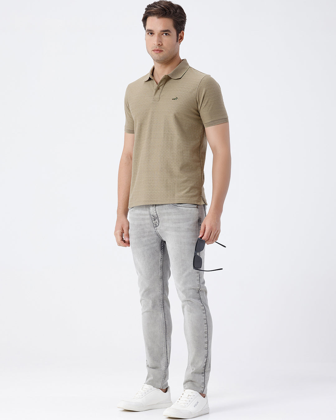 Man wearing a grey light grey knit slim fit jeans on a light gray background