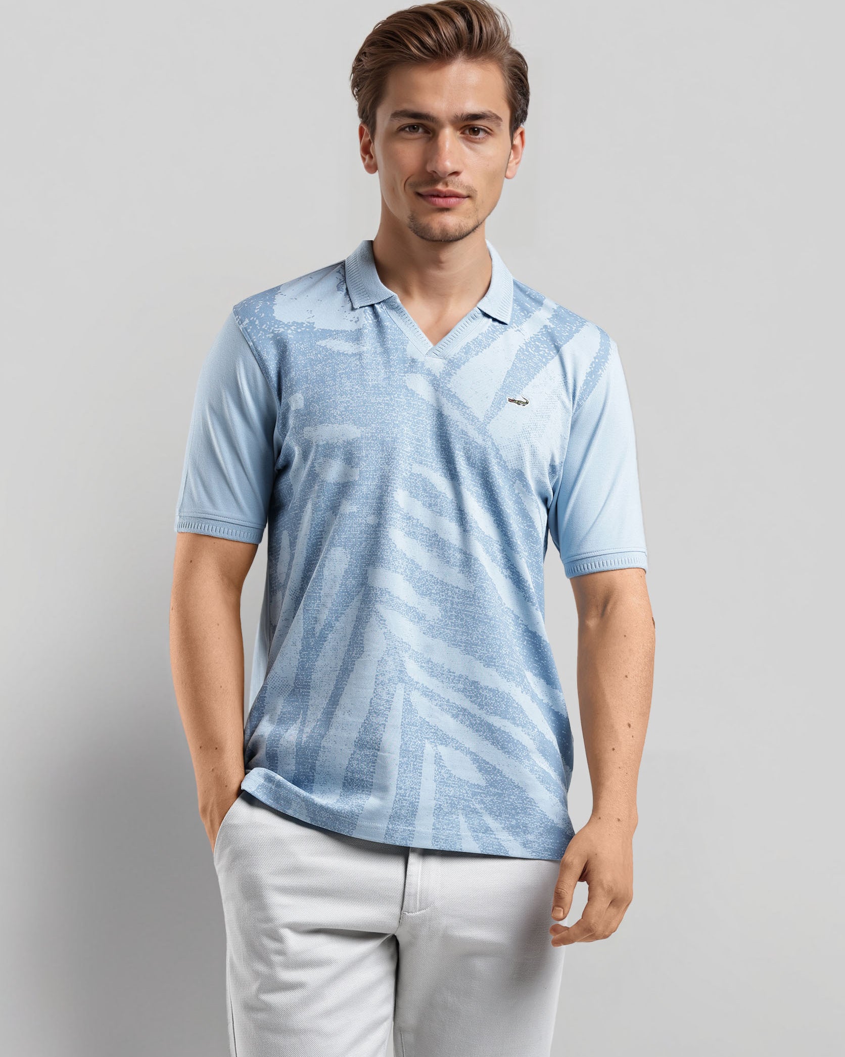 Man wearing a light blue patterned polo shirt and light gray pants on a gray background