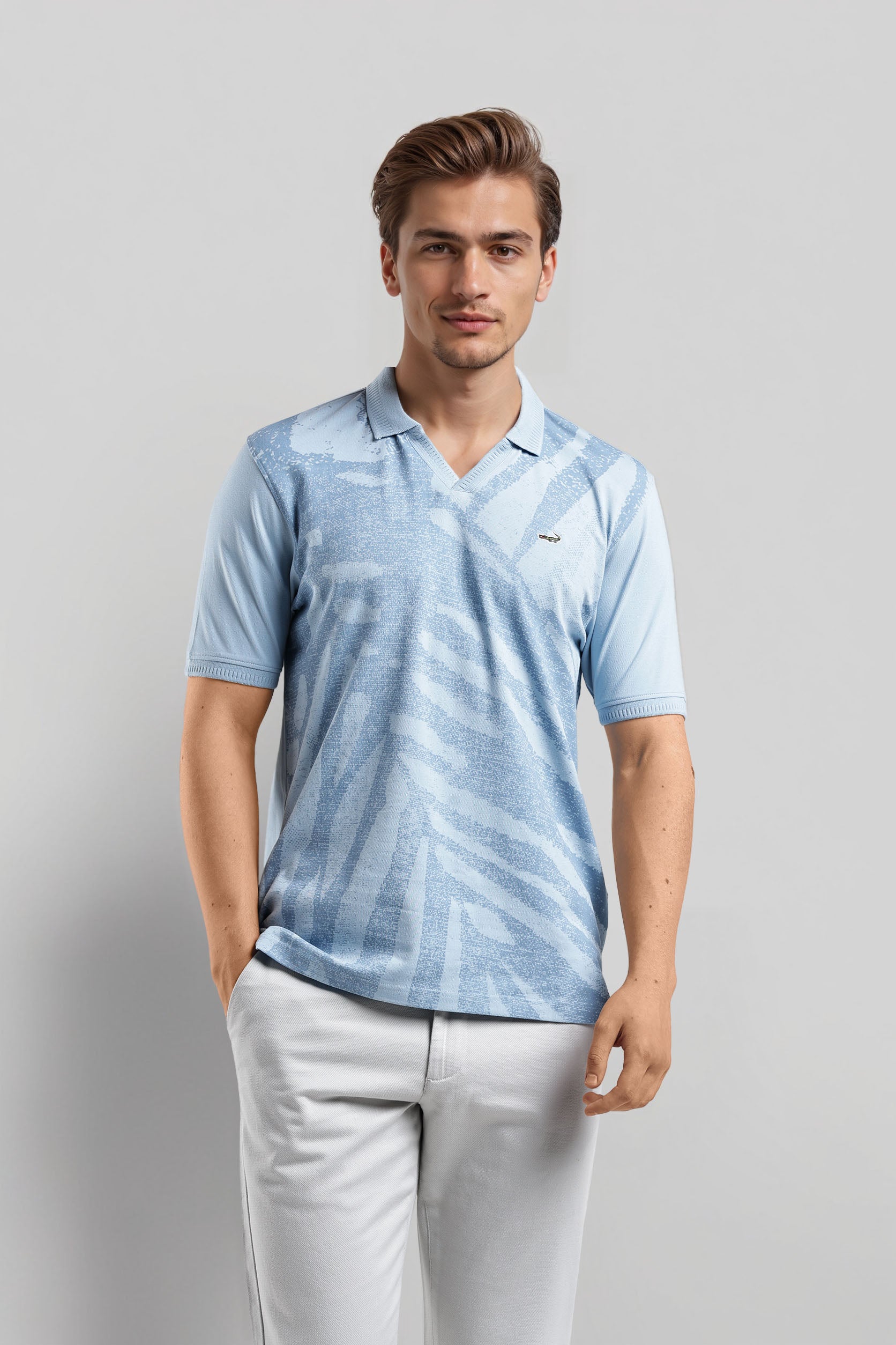 Man wearing a light blue patterned polo shirt and light gray pants on a gray background