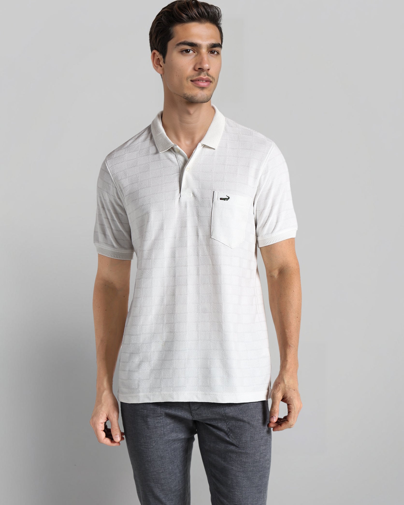 Man wearing a light gray polo shirt and dark gray pants on a plain background