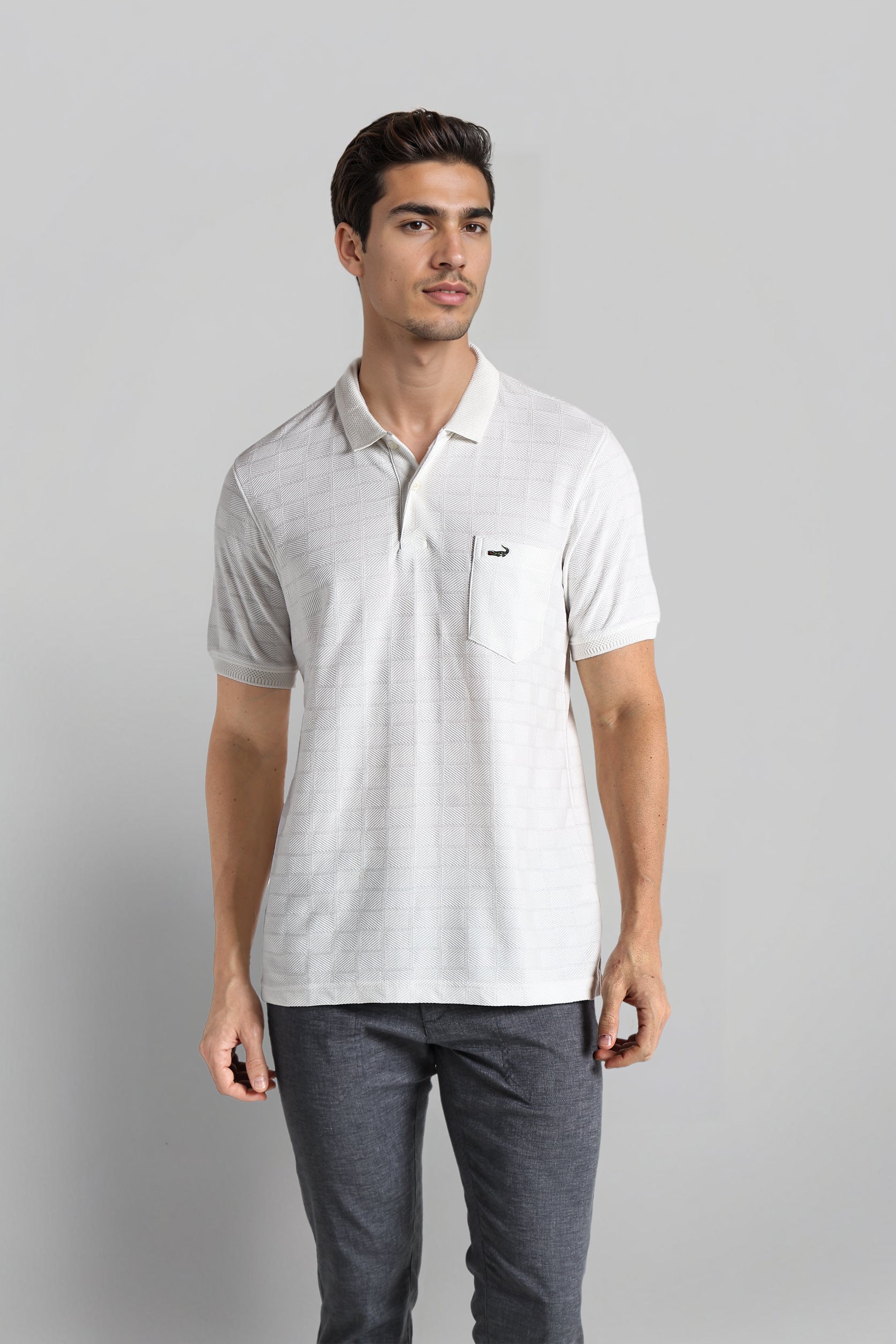 Man wearing a light gray polo shirt and dark gray pants on a plain background