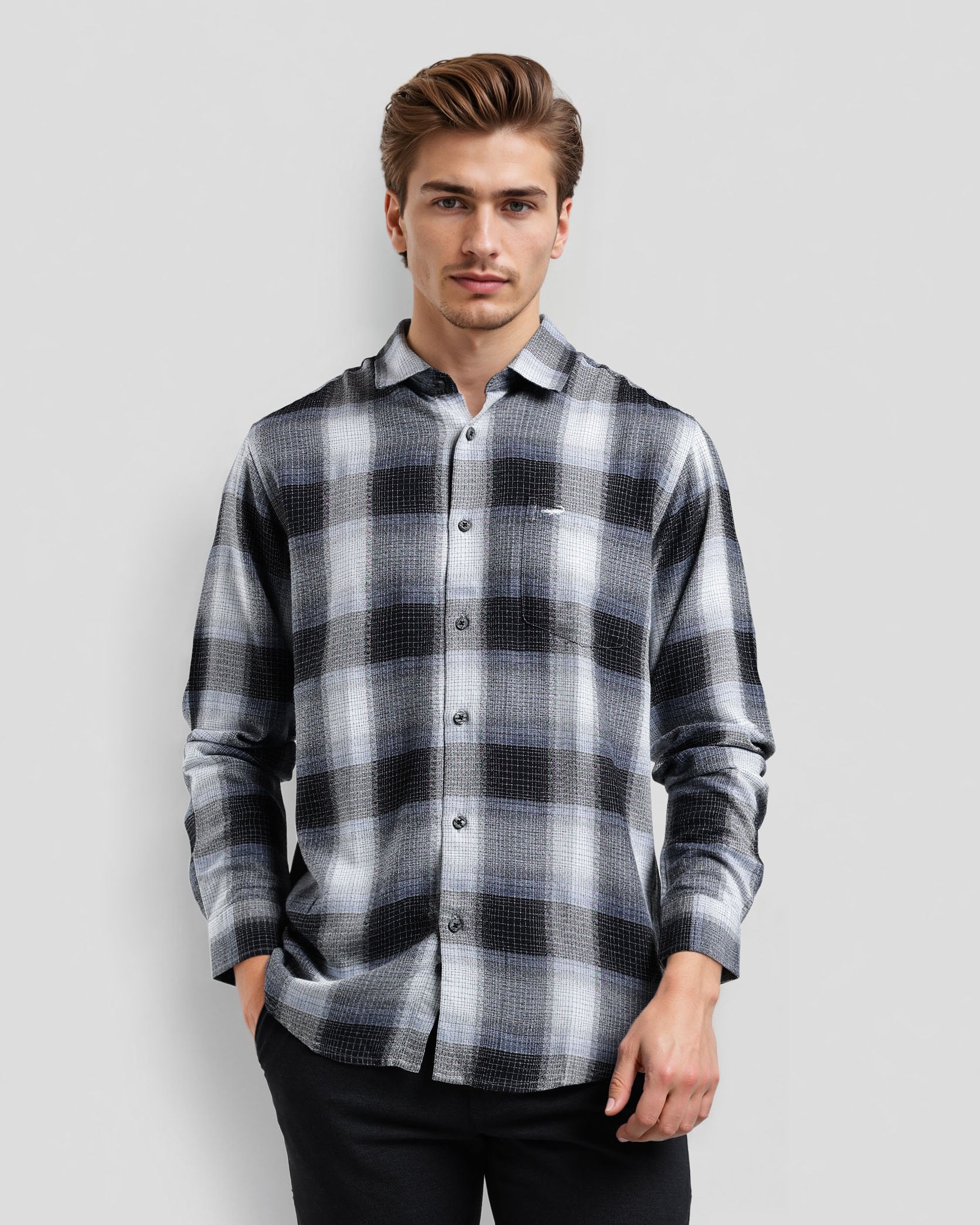 Man wearing a black and gray plaid shirt against a light gray background