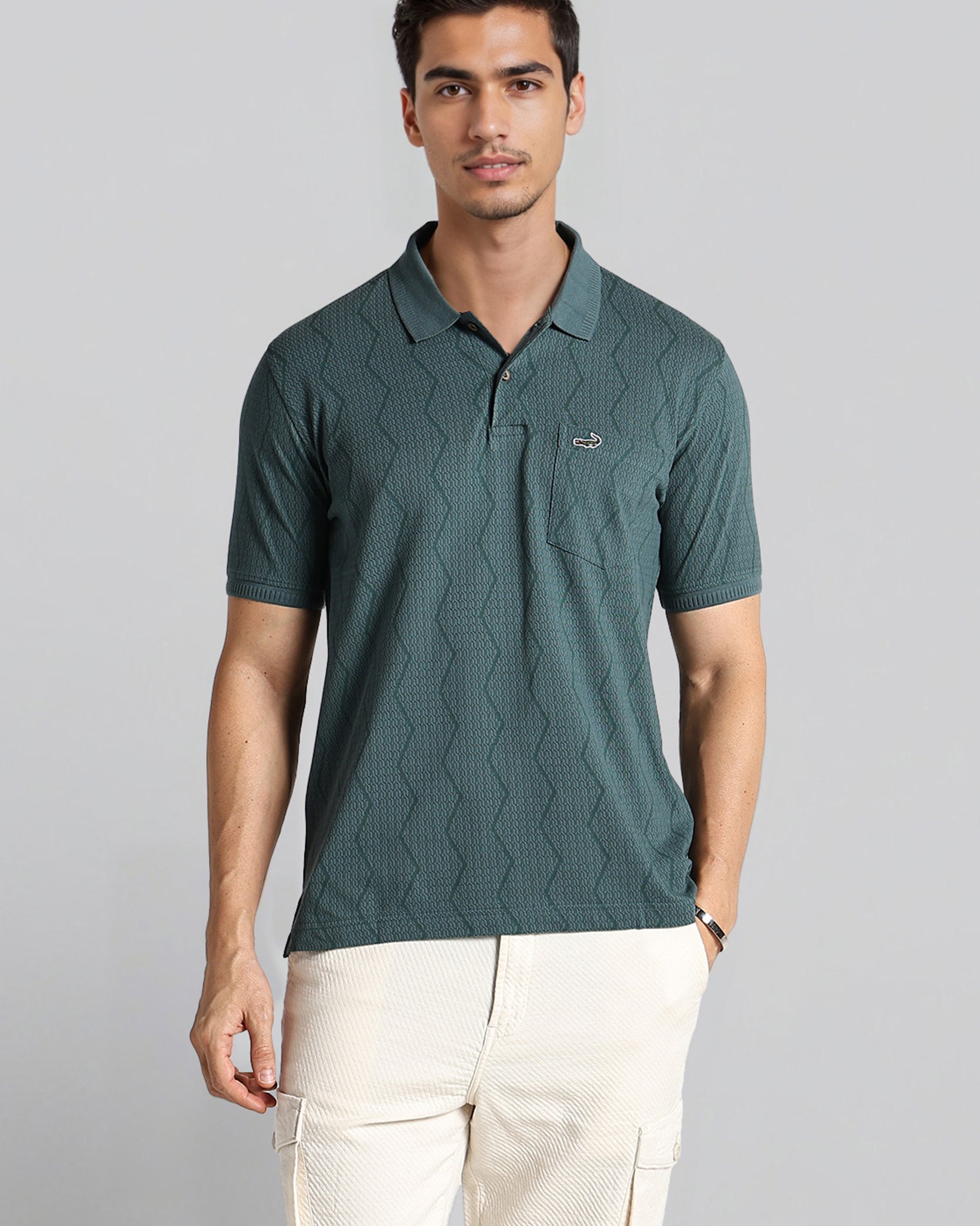 Man wearing a green textured polo shirt with a logo on a gray background