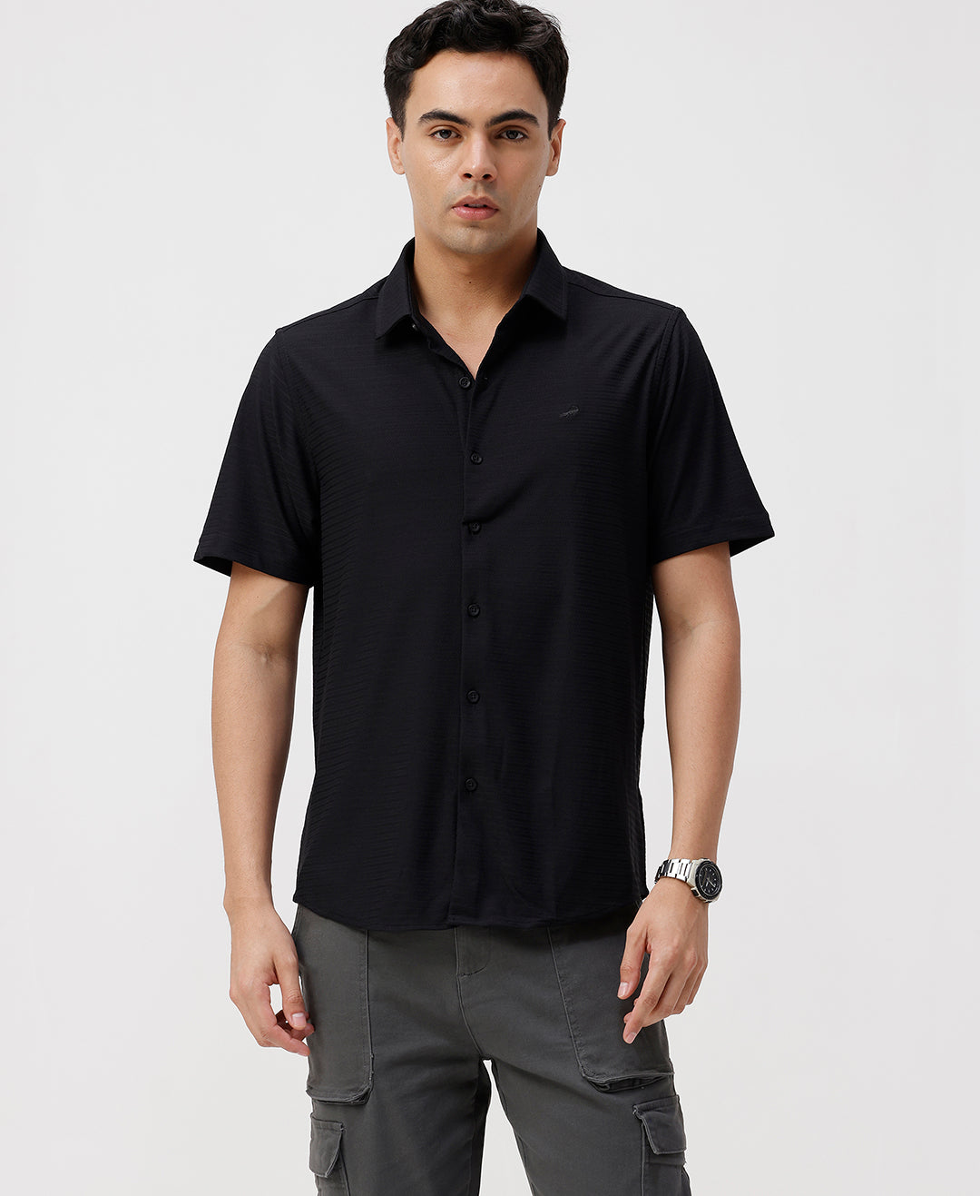 Man wearing a black solid black cotton shirt with casual styling on a gray background