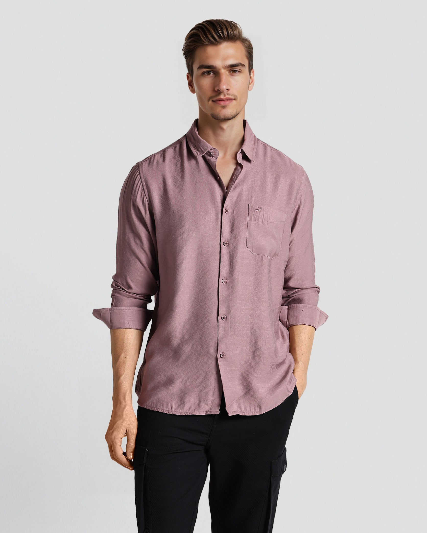 Man wearing a pink shirt and black pants on a white background