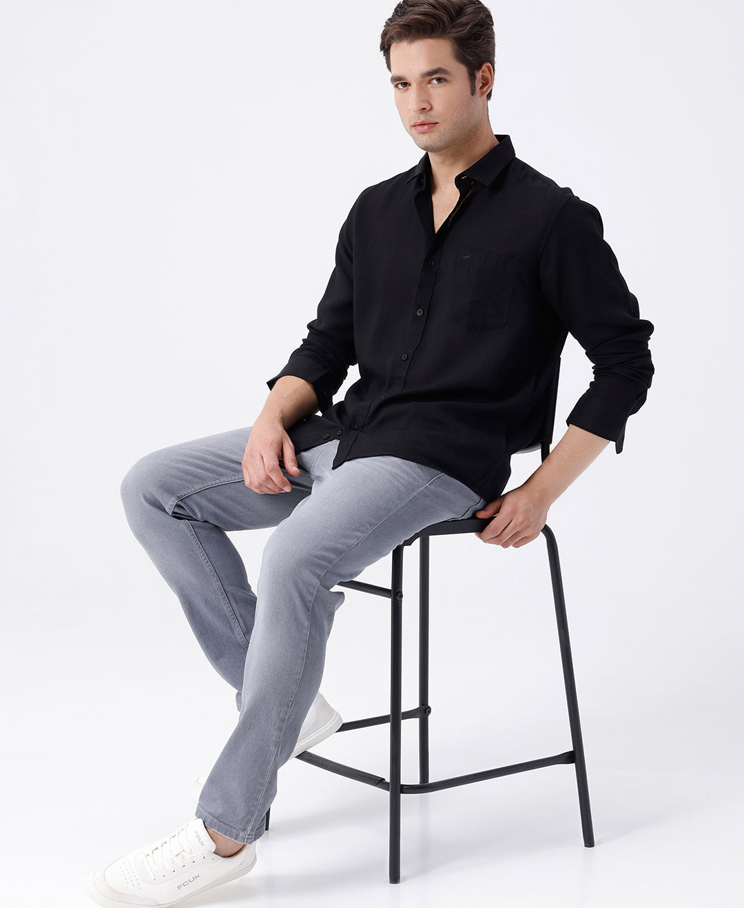 Man wearing a black linen blend shirt in black with casual styling on a gray background