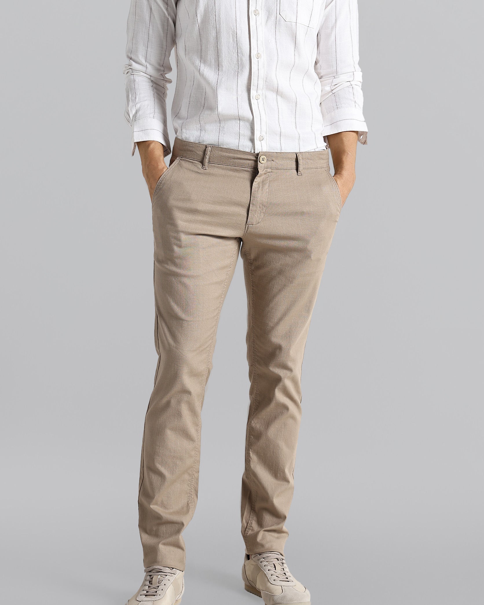 Person wearing a white shirt and beige pants on a gray background