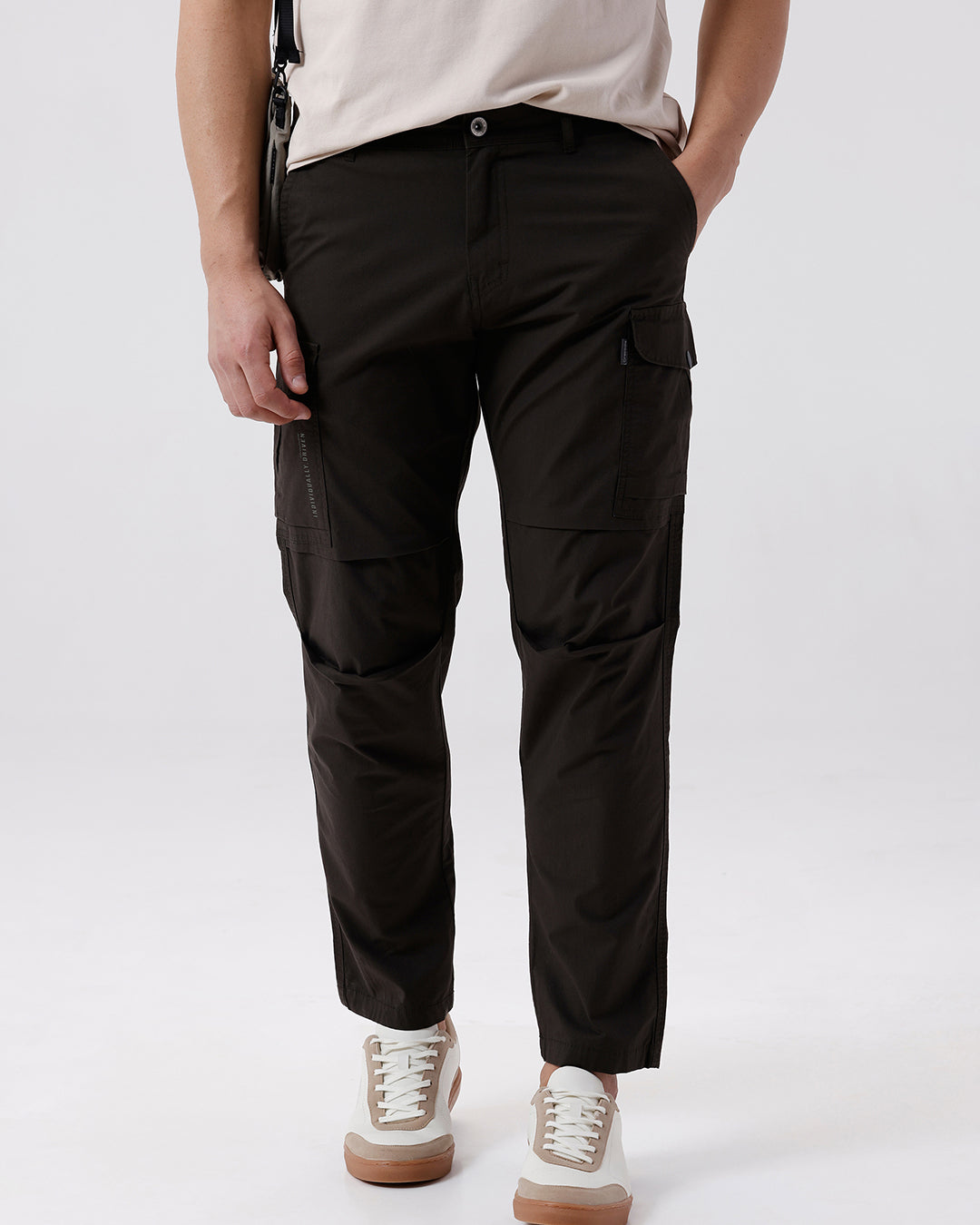 Man wearing a grey utility trekflex cargo pant in dark grey on a light gray background