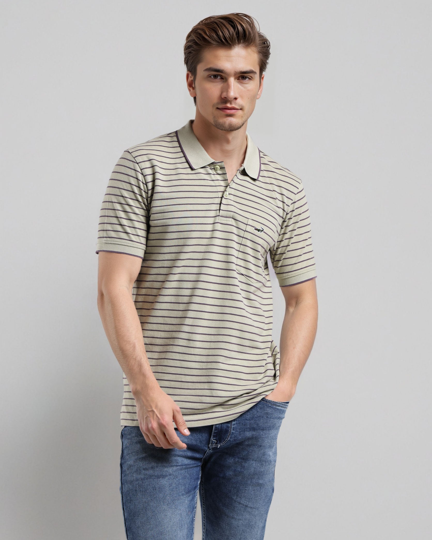 Man wearing a striped polo shirt and jeans against a plain background