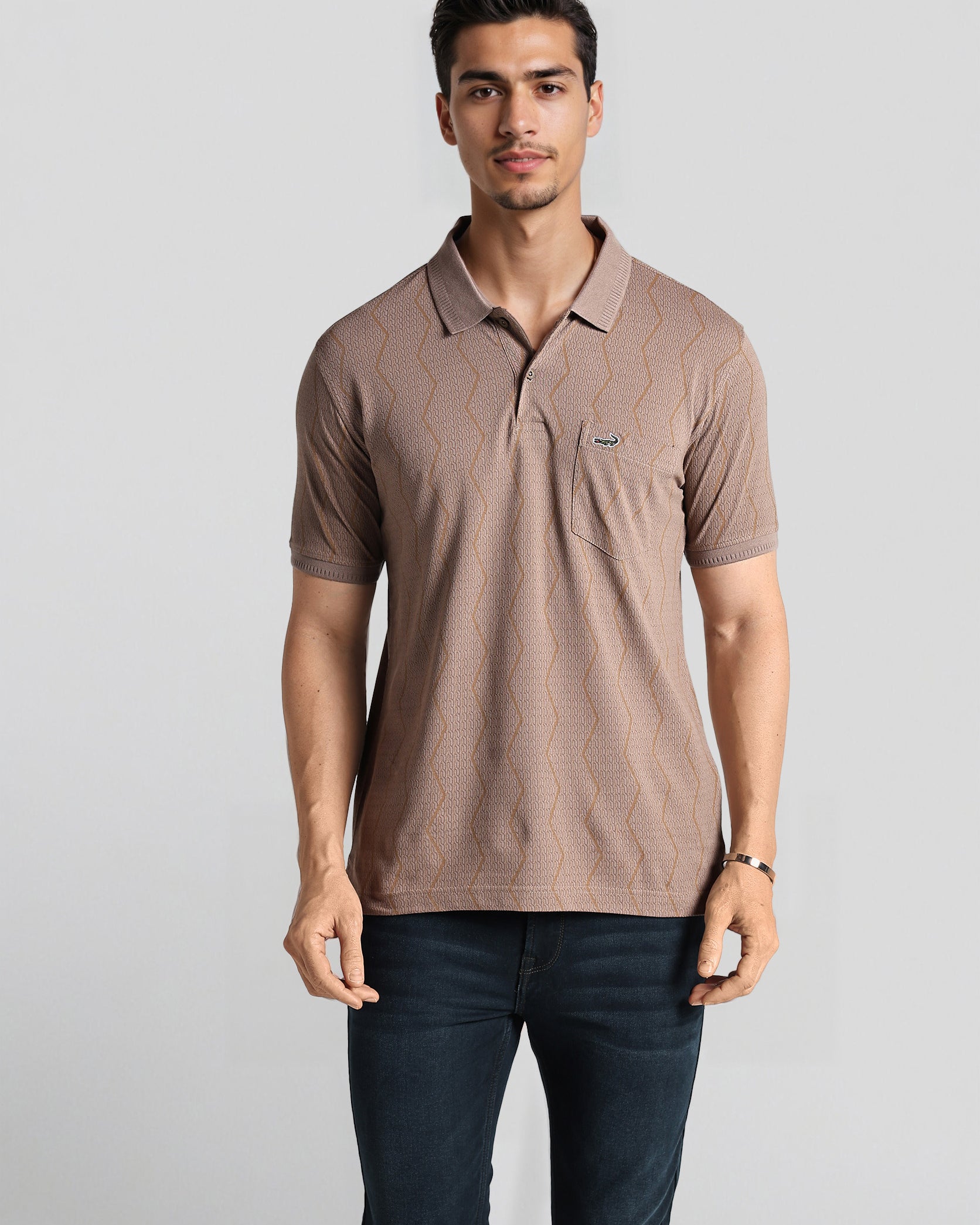 Man wearing a brown polo shirt with a logo on a light gray background