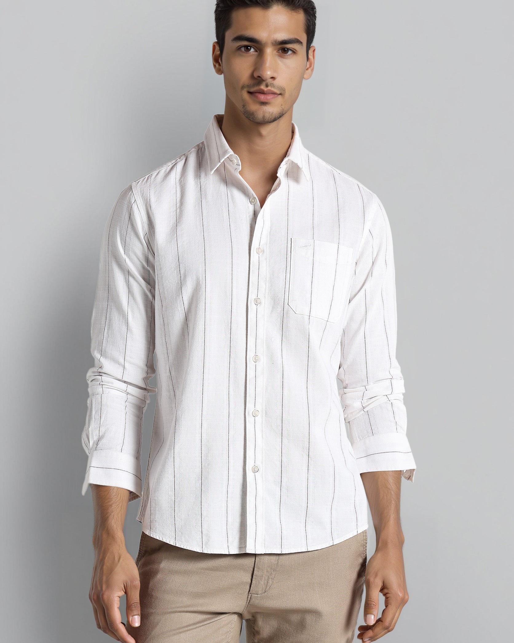 Man wearing a white striped shirt and beige pants against a gray background
