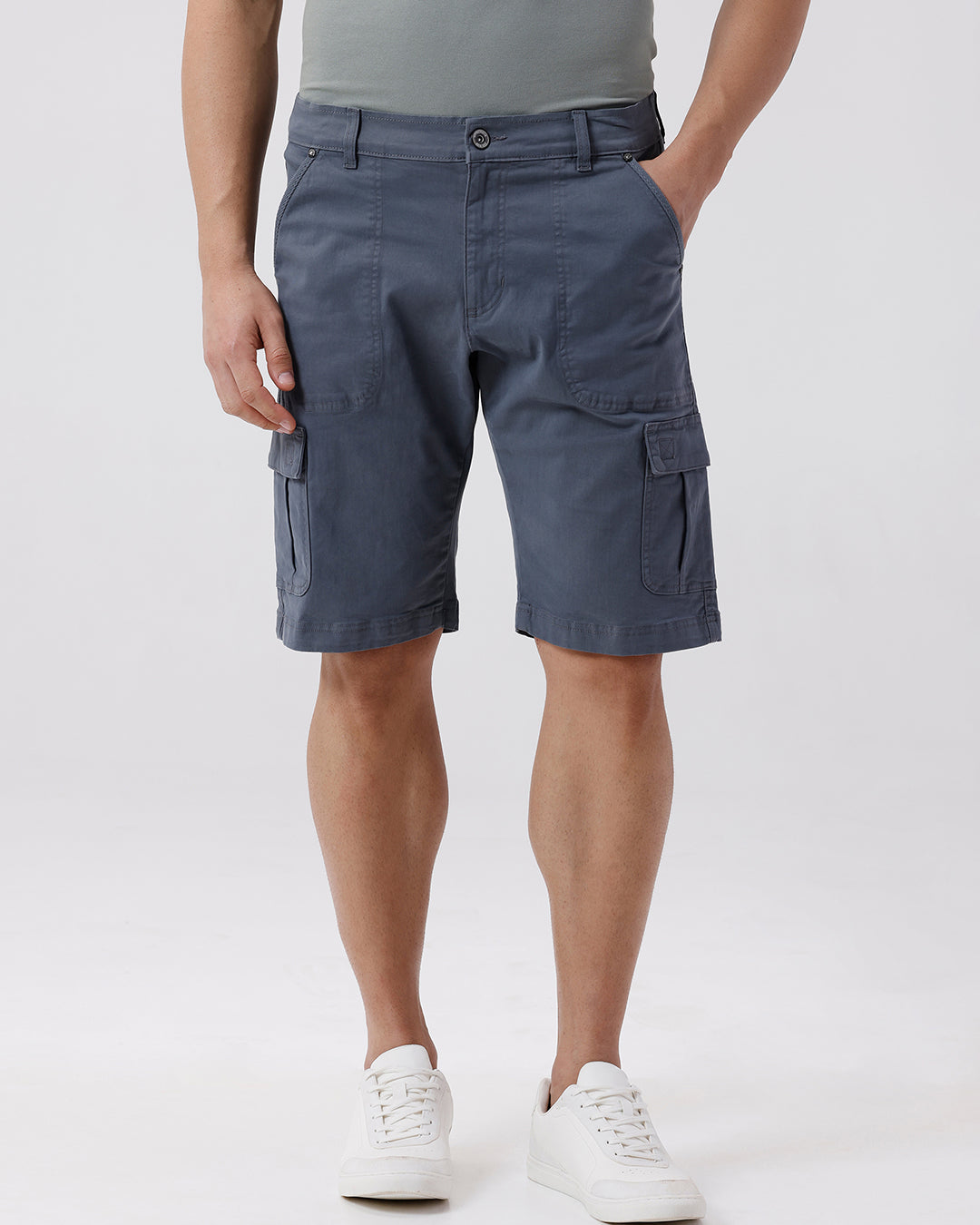 Man wearing a grey garment dyed cargo shorts in dark grey with casual styling on a gray background