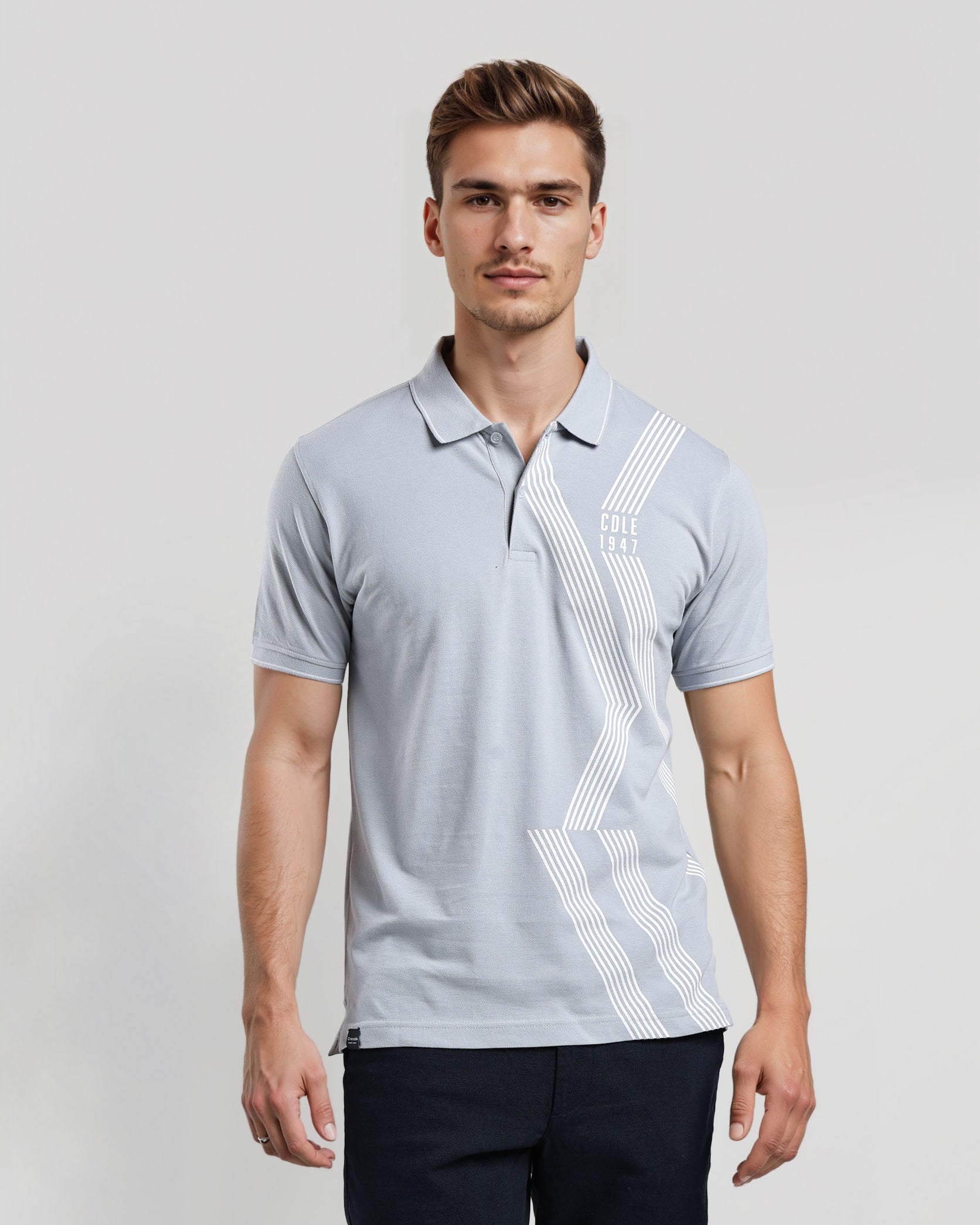 Man wearing a light gray polo shirt with a geometric pattern on a white background