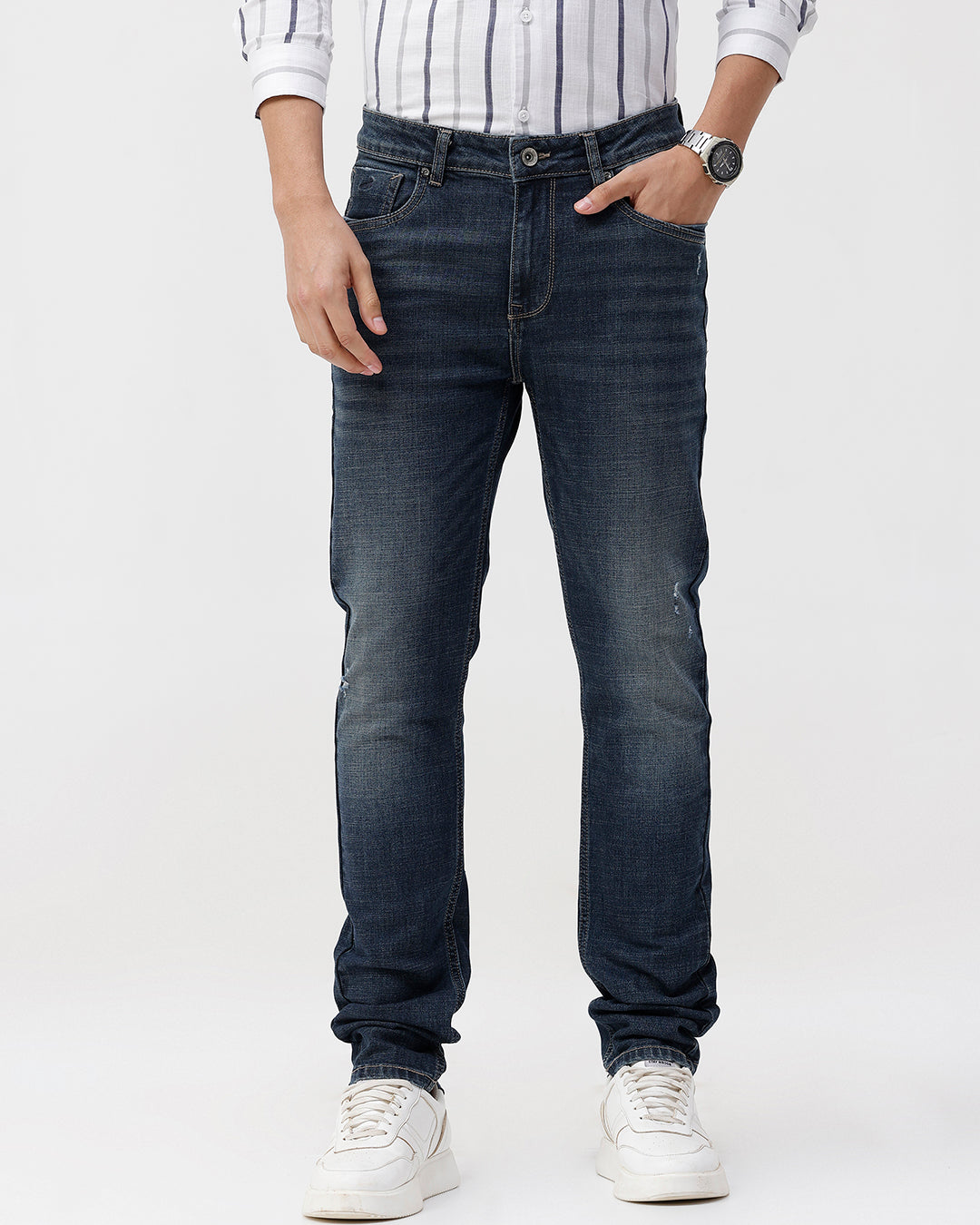 Man wearing a blue blue twill slim fit jeans with casual styling on a gray background
