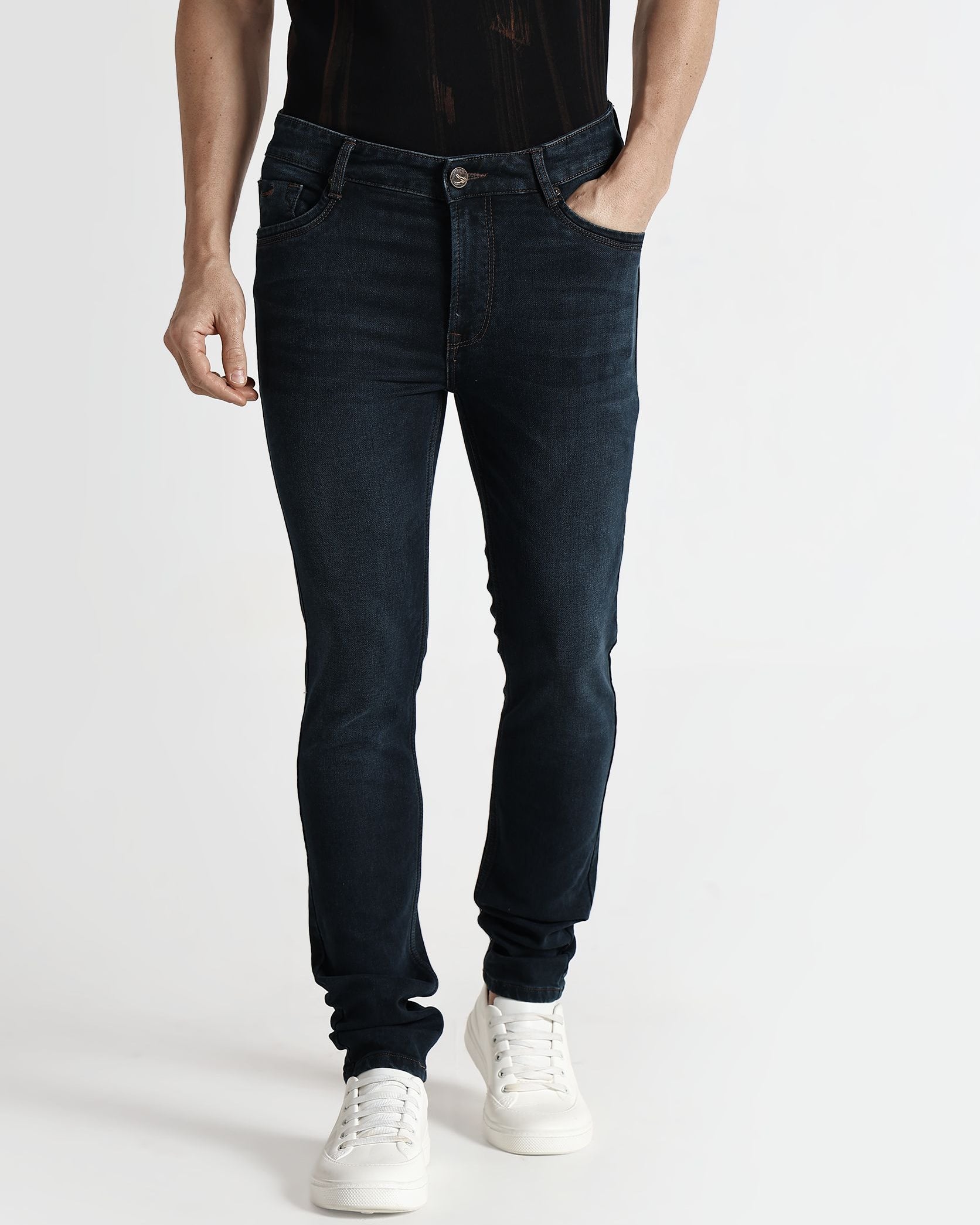 Person wearing black jeans and white sneakers on a white background