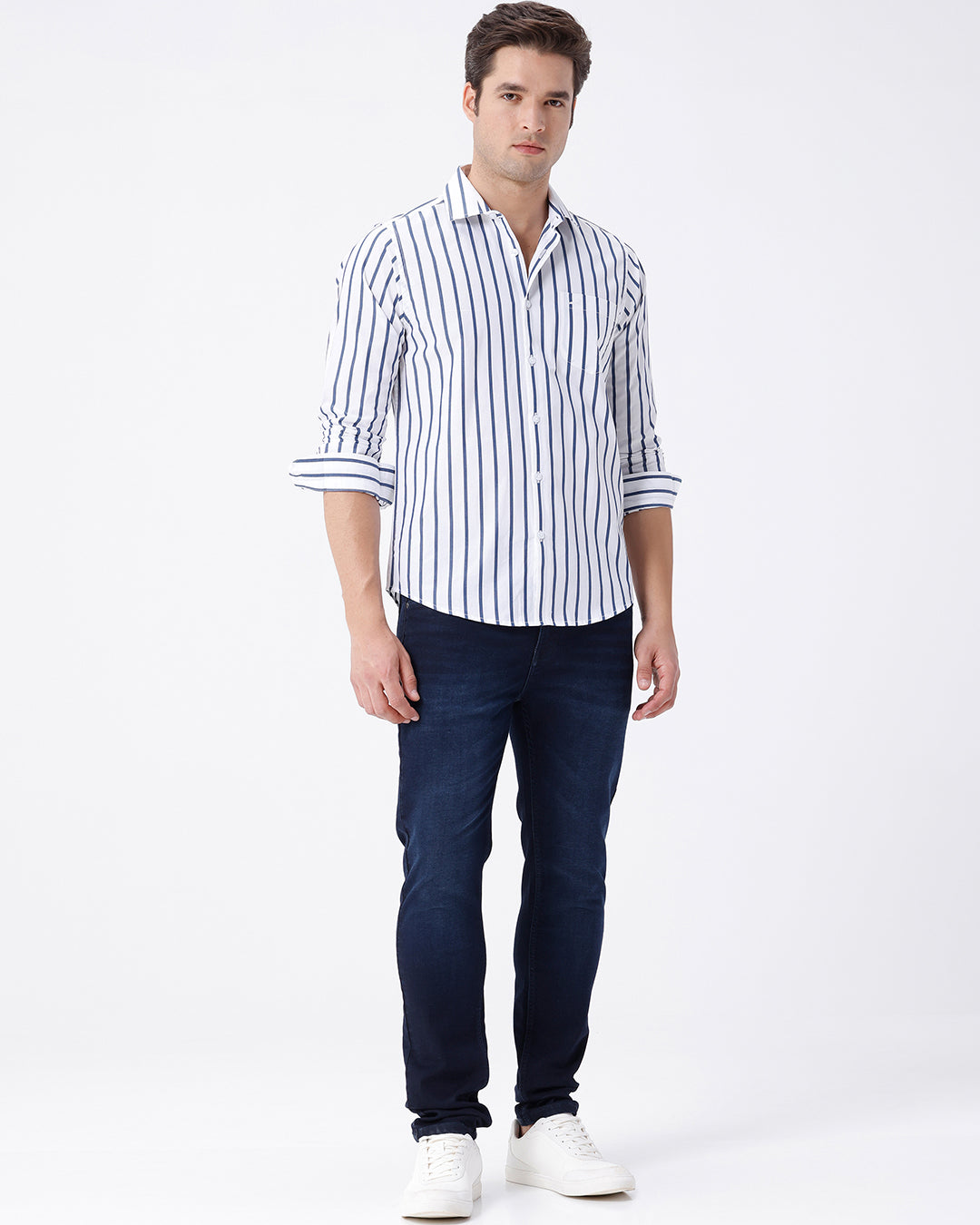 Man wearing a blue dark blue knit slim fit jeans with casual styling on a gray background