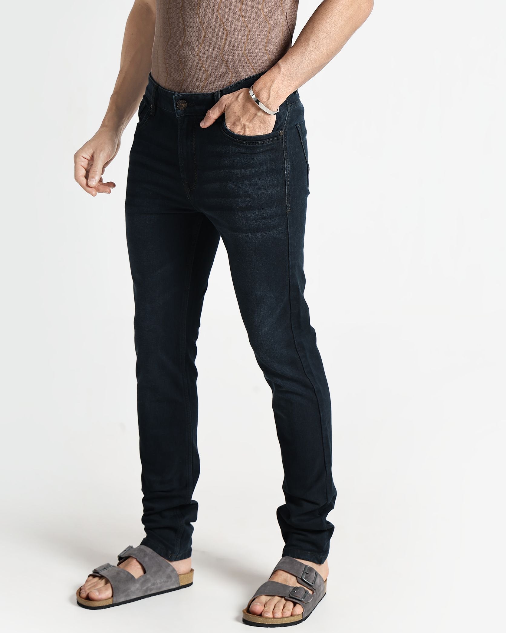 Person wearing black jeans and sandals on a white background