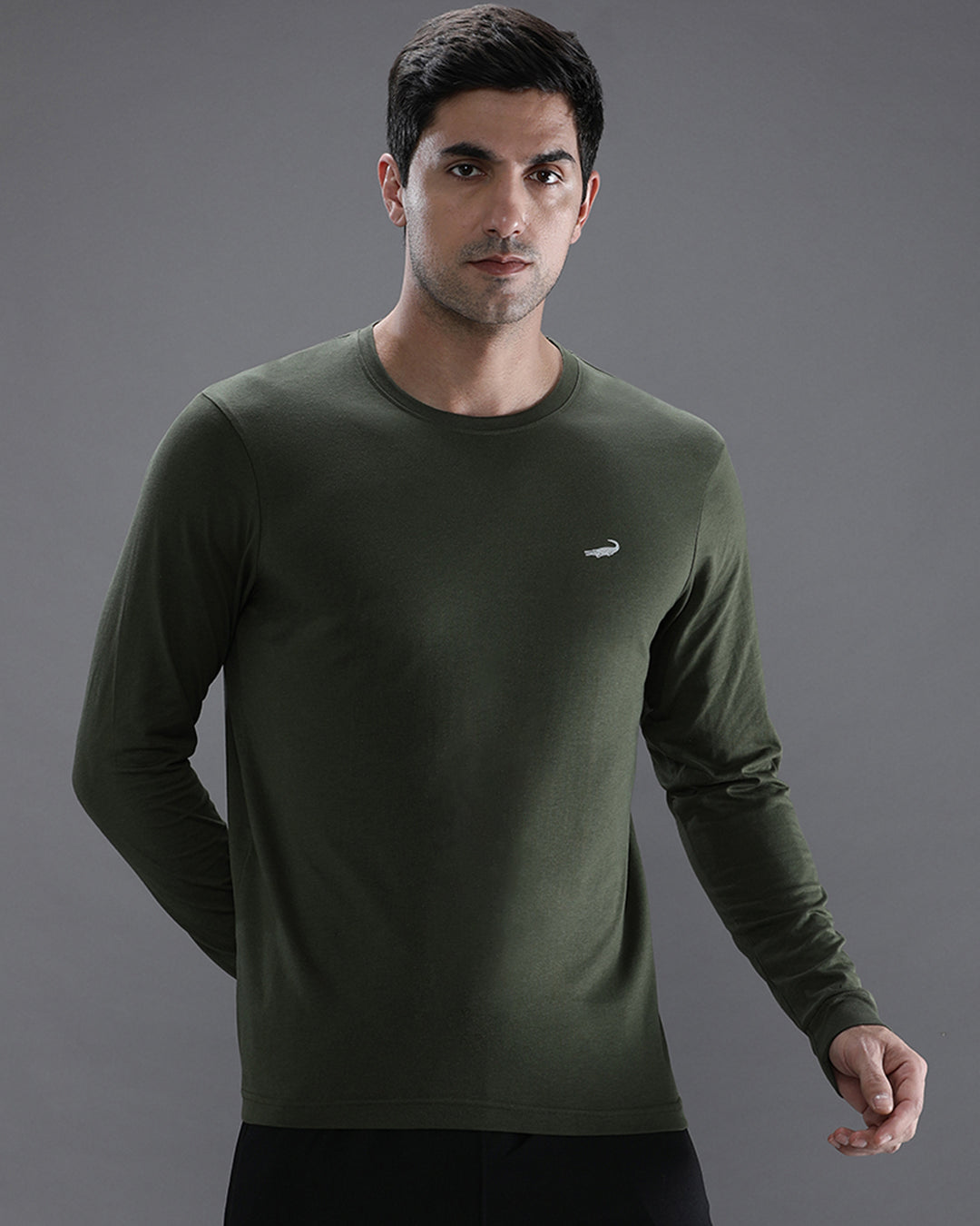 Man wearing a green solid green sport fit t shirt with casual styling on a gray background