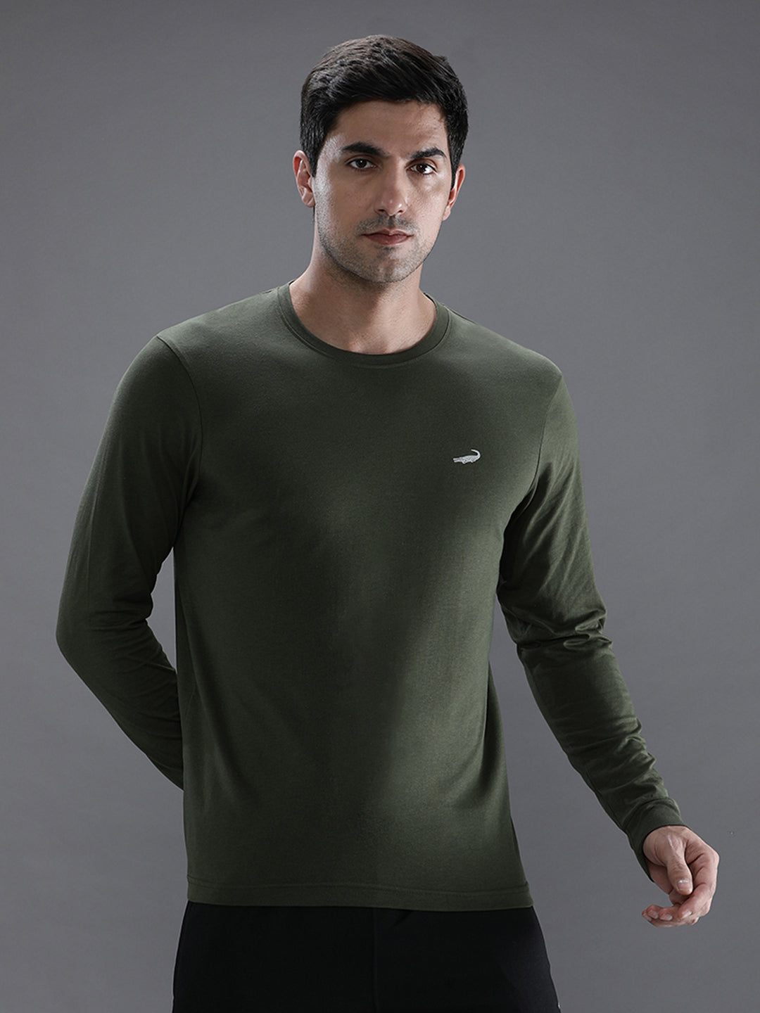 Man wearing a green solid green sport fit t shirt with casual styling on a gray background