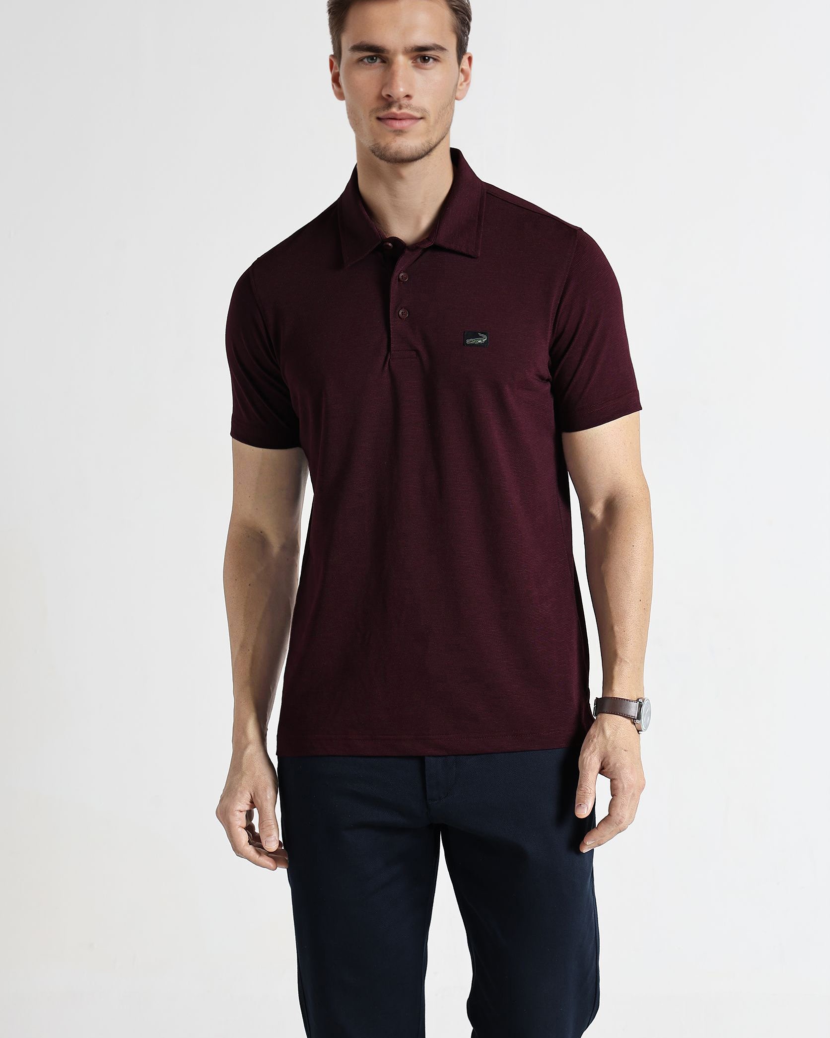 Man wearing a maroon polo shirt with a small logo on a white background