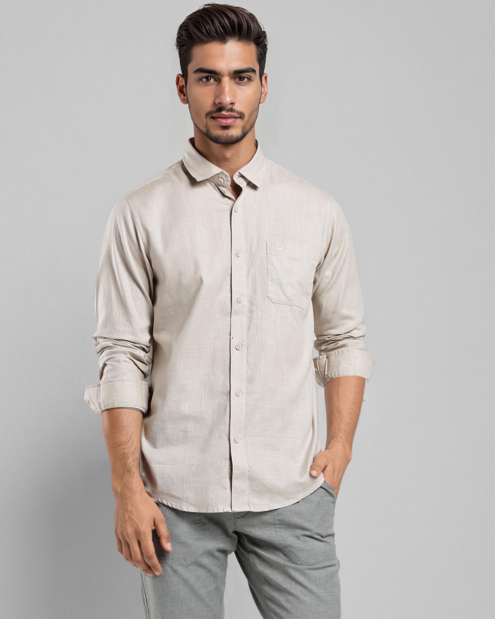 Man wearing a beige shirt and gray pants against a gray background