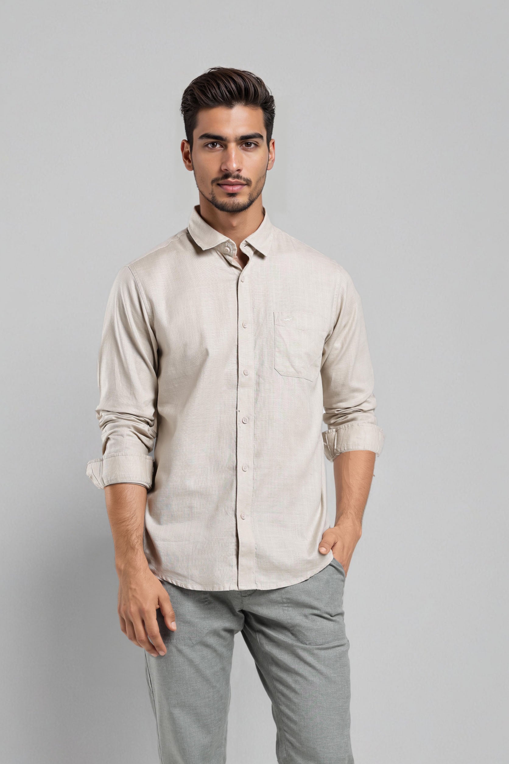 Man wearing a beige shirt and gray pants against a gray background